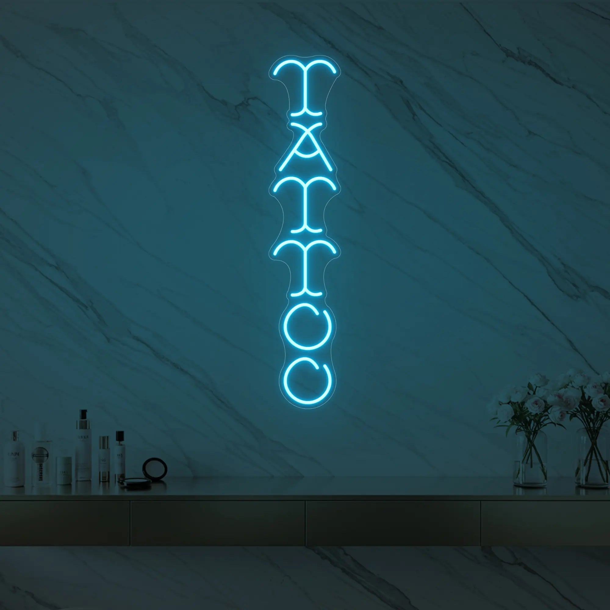 Photo of the 'Vertical Tattoo' neon sign glowing in ice blue against a styled interior wall.