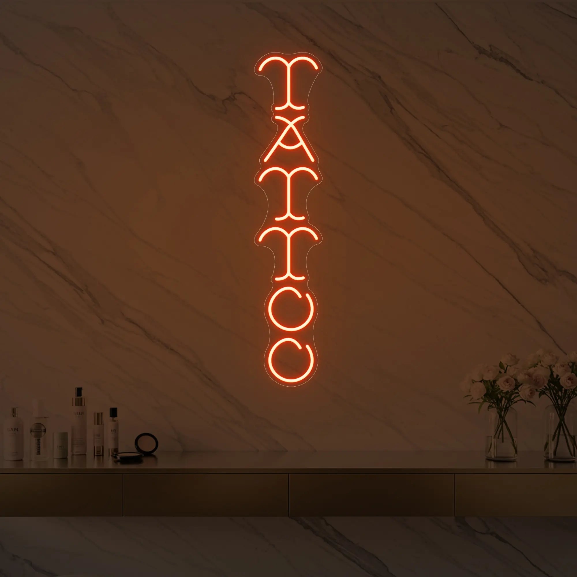 Photo of the 'Vertical Tattoo' neon sign glowing in golden yellow against a styled interior wall.