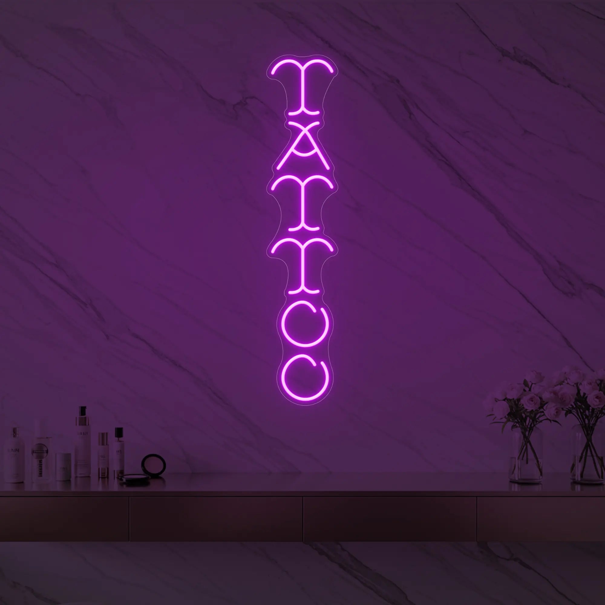 Photo of the 'Vertical Tattoo' neon sign glowing in deep pink against a styled interior wall.