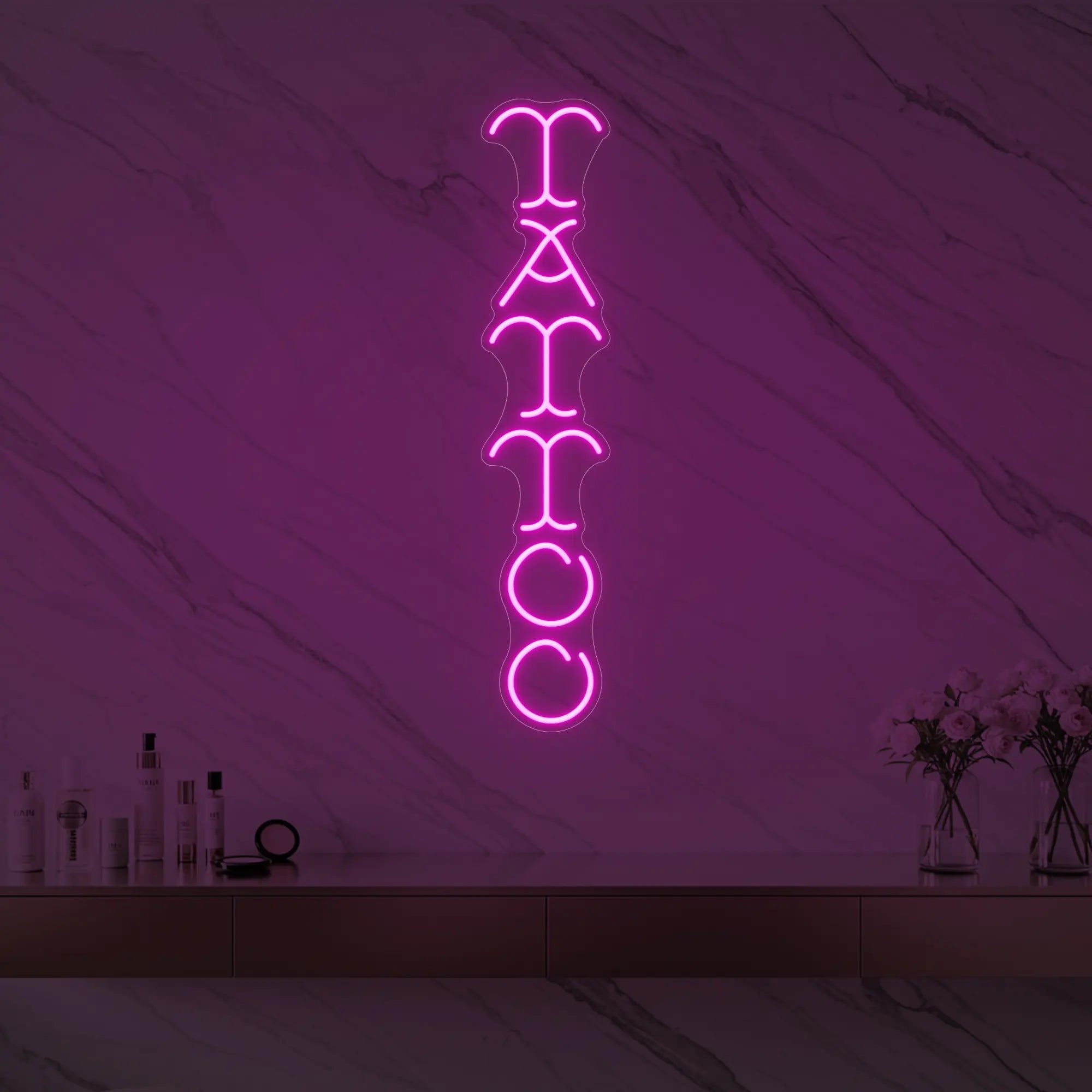 Photo of the 'Vertical Tattoo' neon sign glowing in light pink against a styled interior wall.