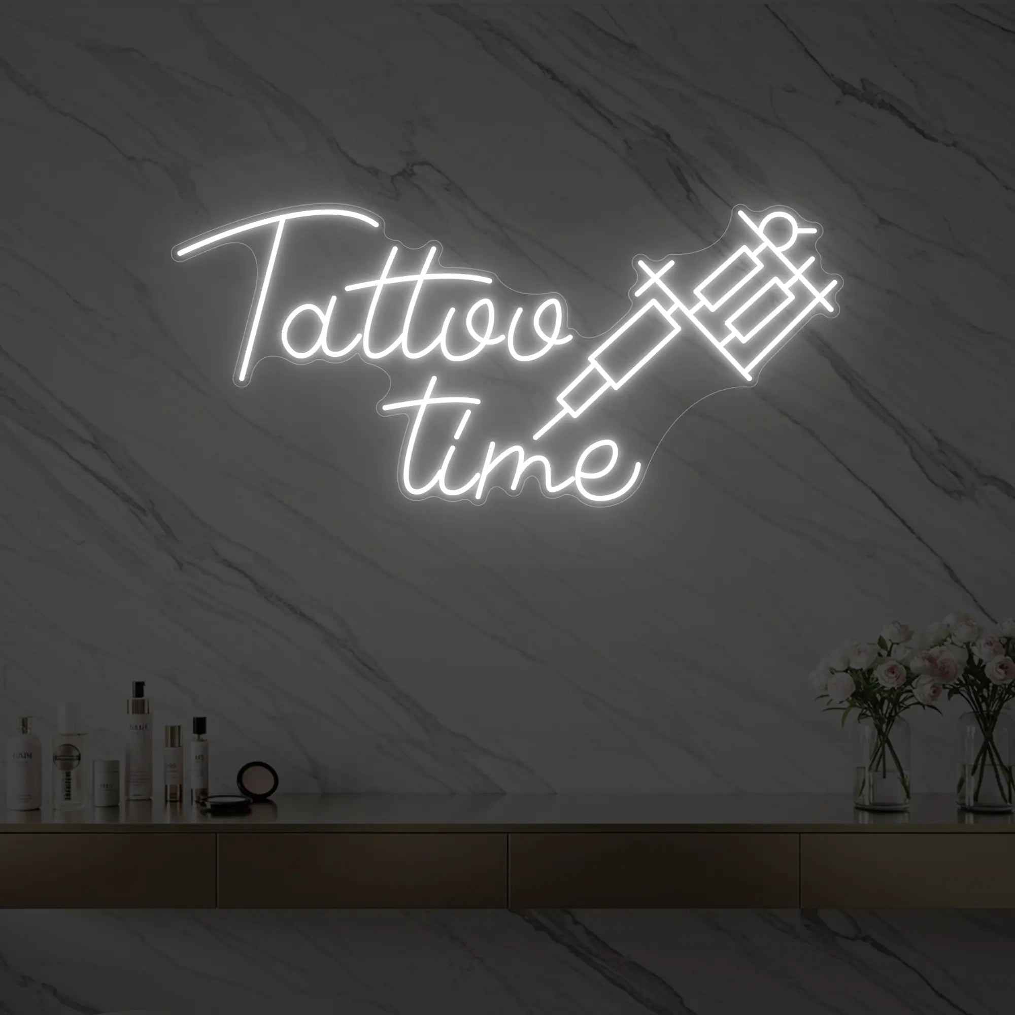 Photo of the 'Tattoo Time' neon sign glowing in cool white against a styled interior wall.