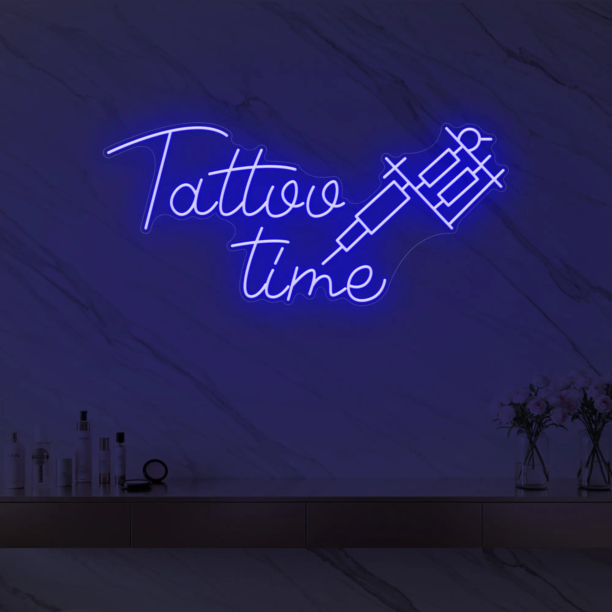 Photo of the 'Tattoo Time' neon sign glowing in deep blue against a styled interior wall.