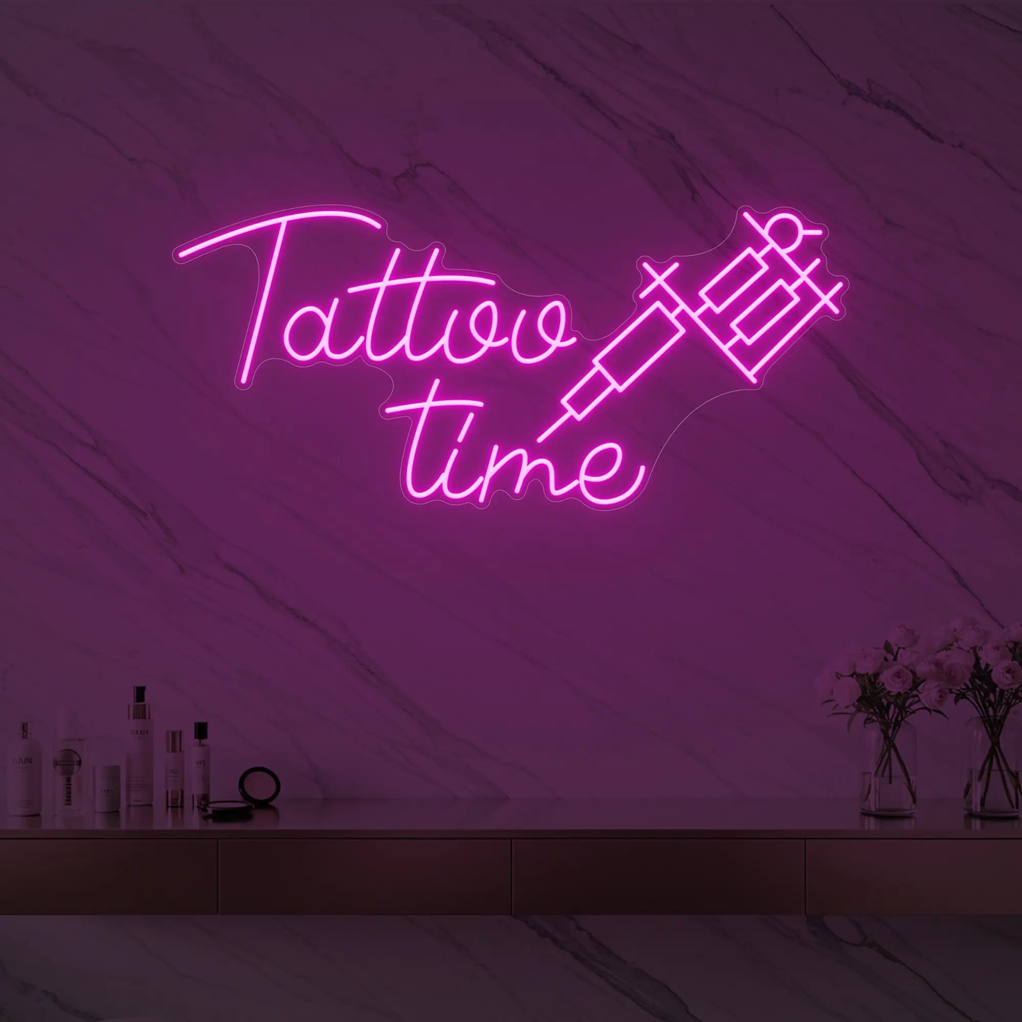 Photo of the 'Tattoo Time' neon sign glowing in light pink against a styled interior wall.