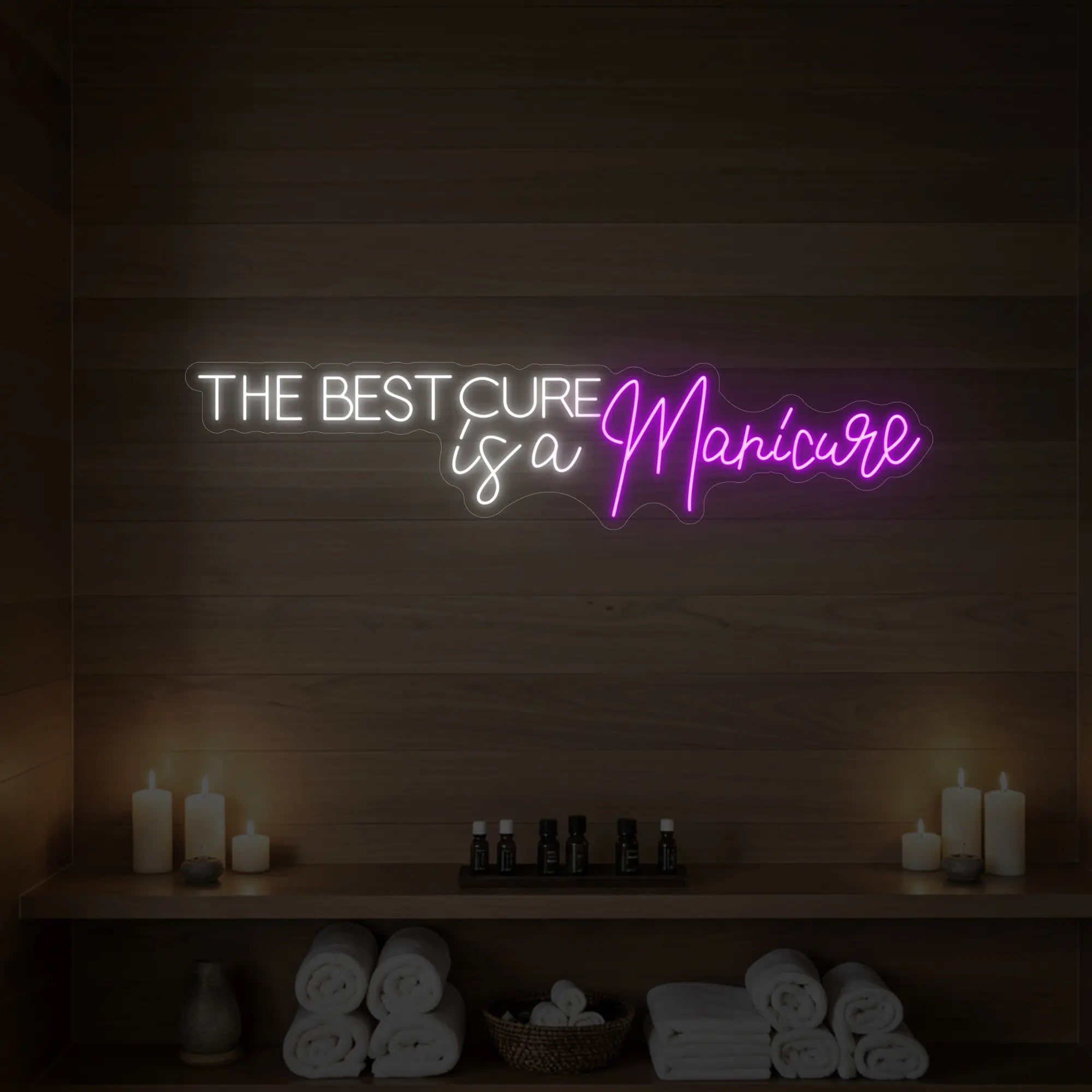 Photo of the 'The Best Cure is a Manicure' neon sign glowing in deep pink against a styled interior wall.