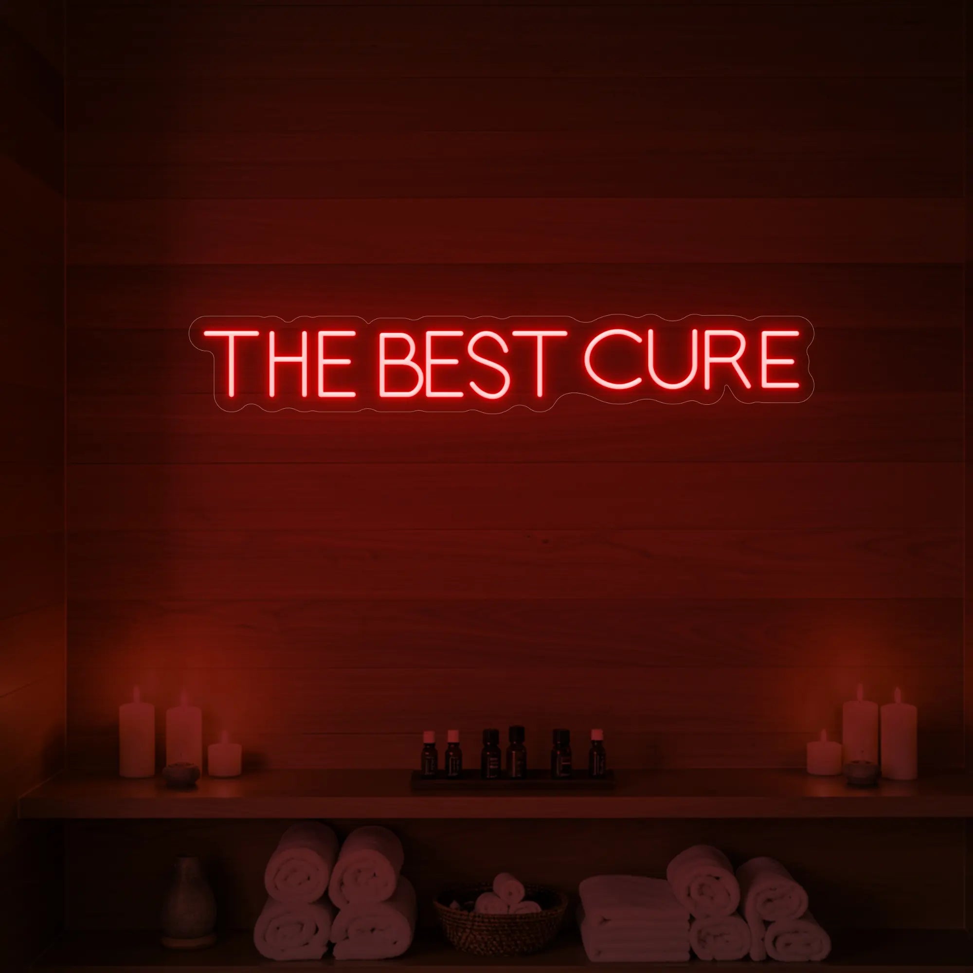 Photo of the 'The Best Cure' neon sign glowing in red against a styled interior wall.