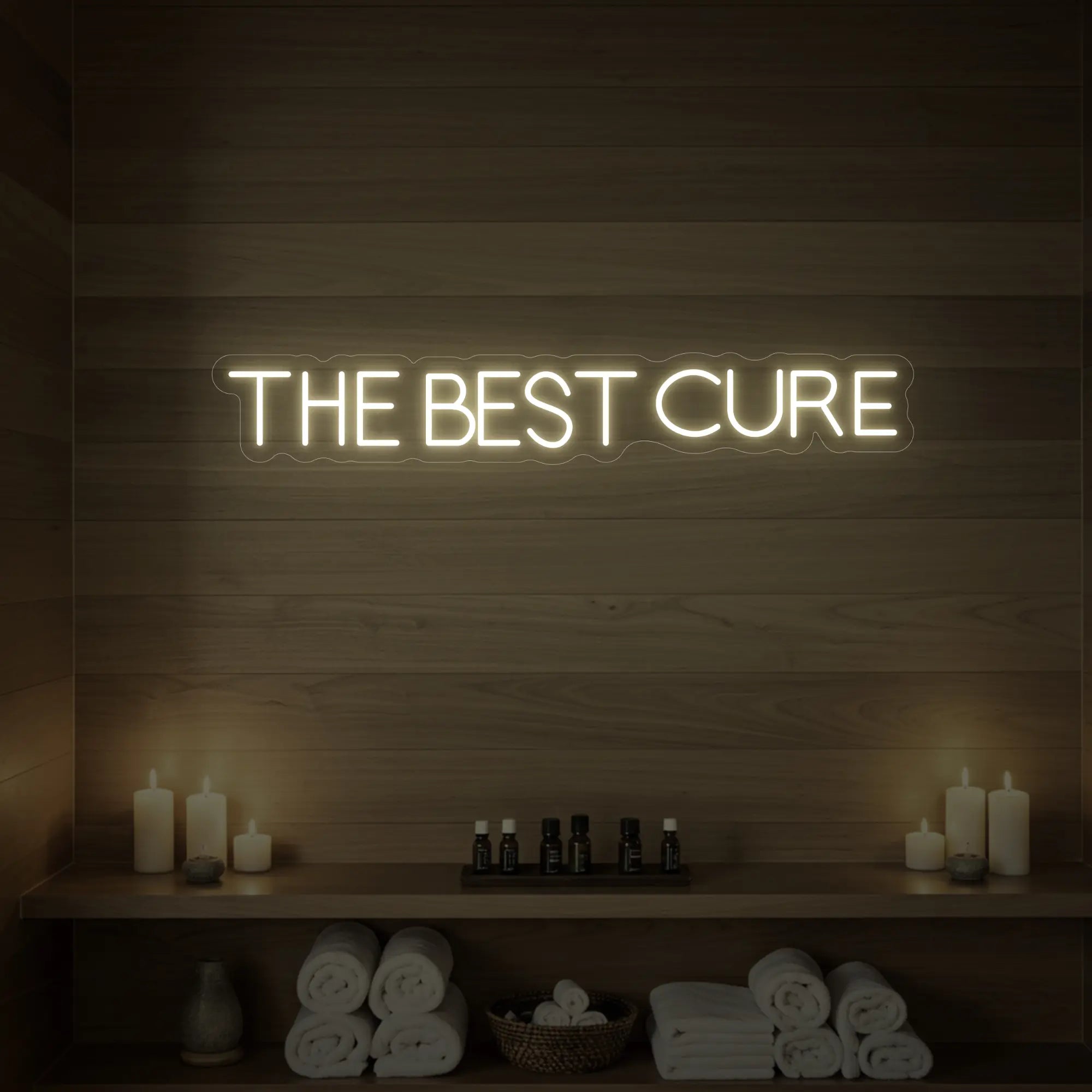 Photo of the 'The Best Cure' neon sign glowing in warm white against a styled interior wall.