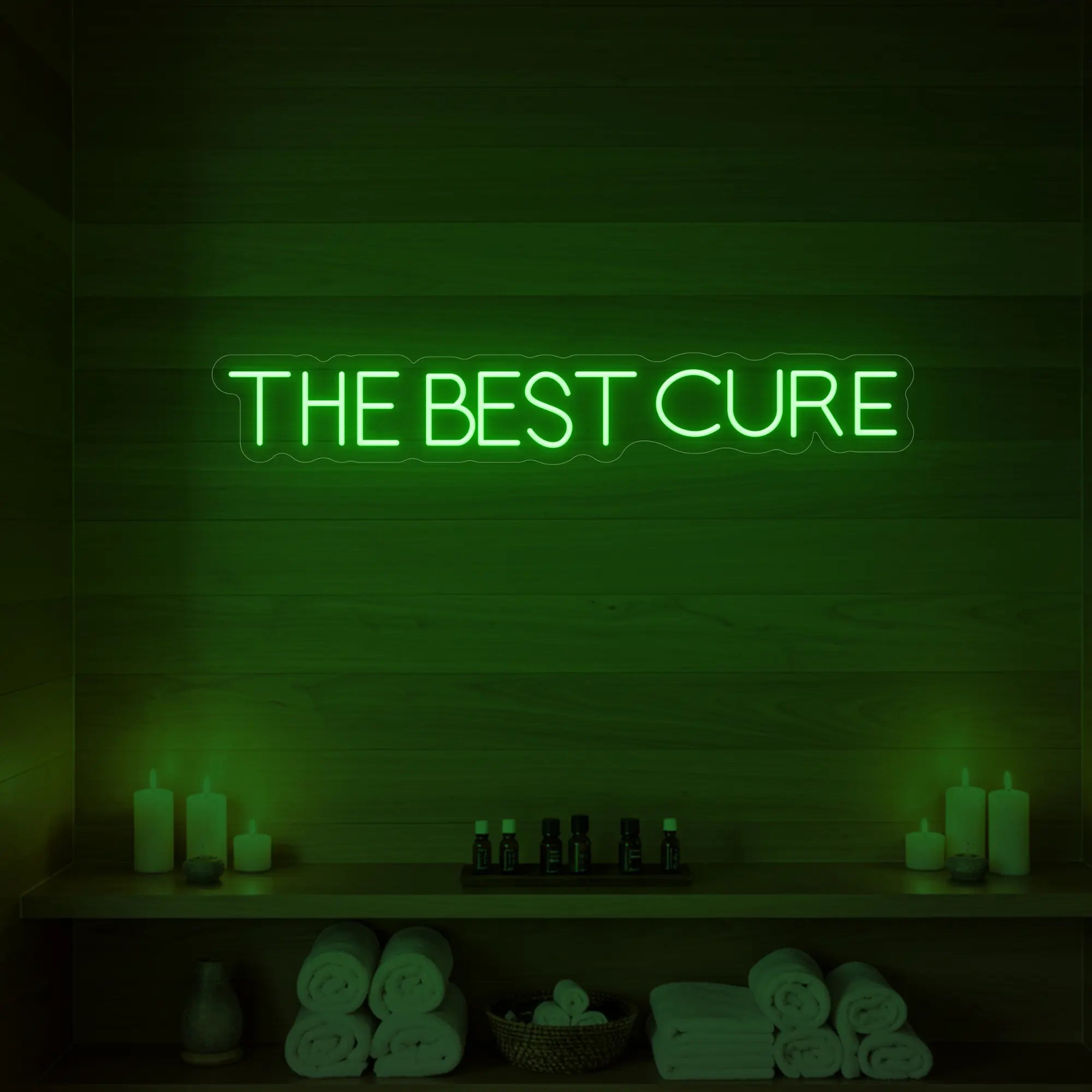 Photo of the 'The Best Cure' neon sign glowing in green against a styled interior wall.