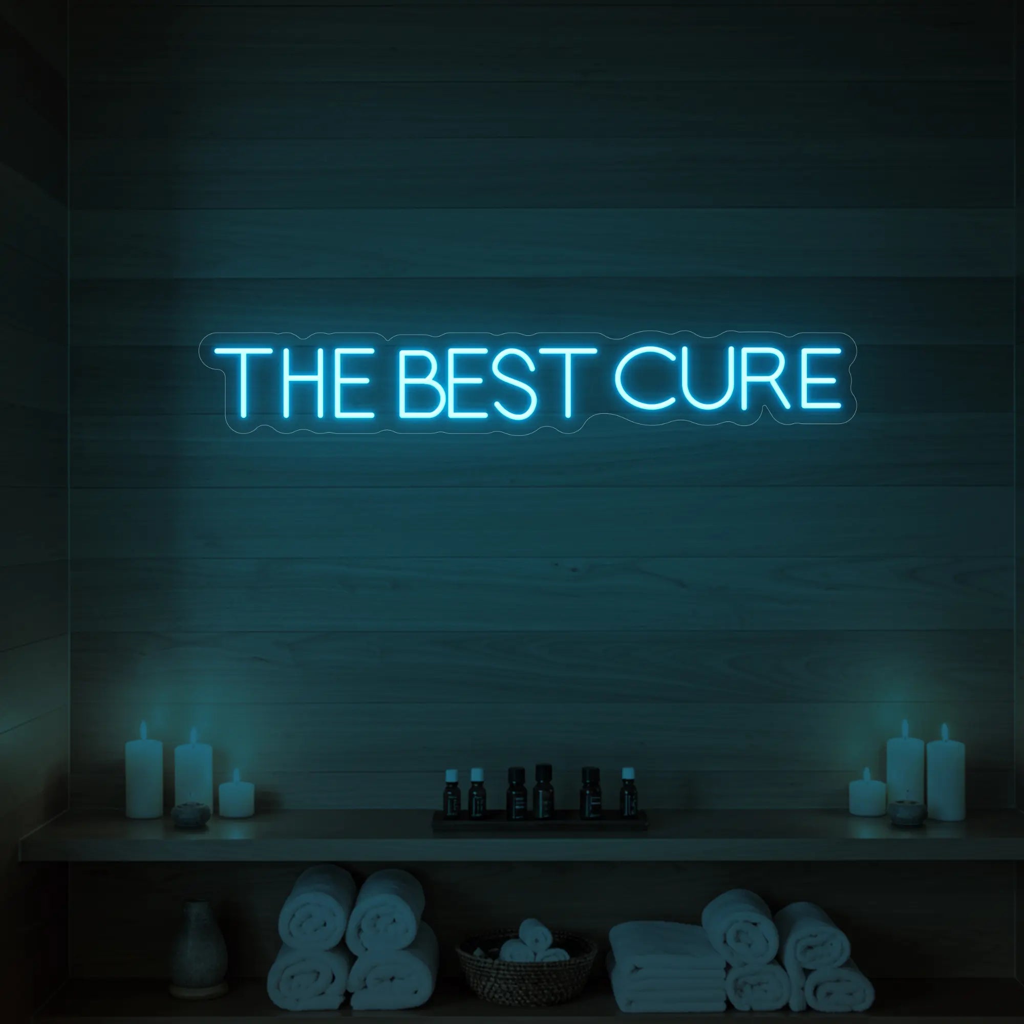 Photo of the 'The Best Cure' neon sign glowing in ice blue against a styled interior wall.