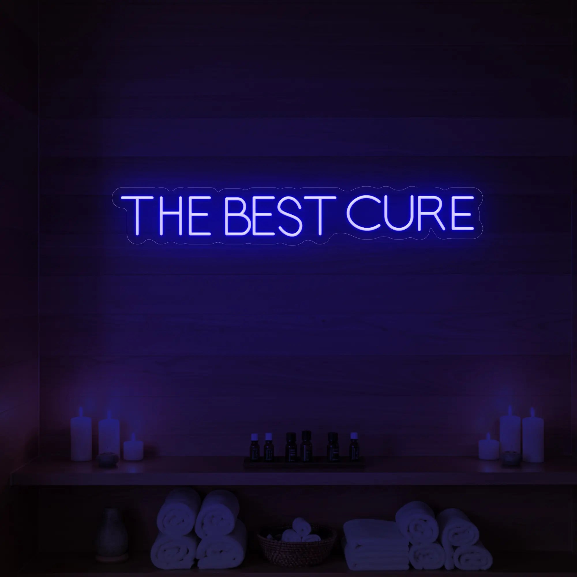 Photo of the 'The Best Cure' neon sign glowing in deep blue against a styled interior wall.