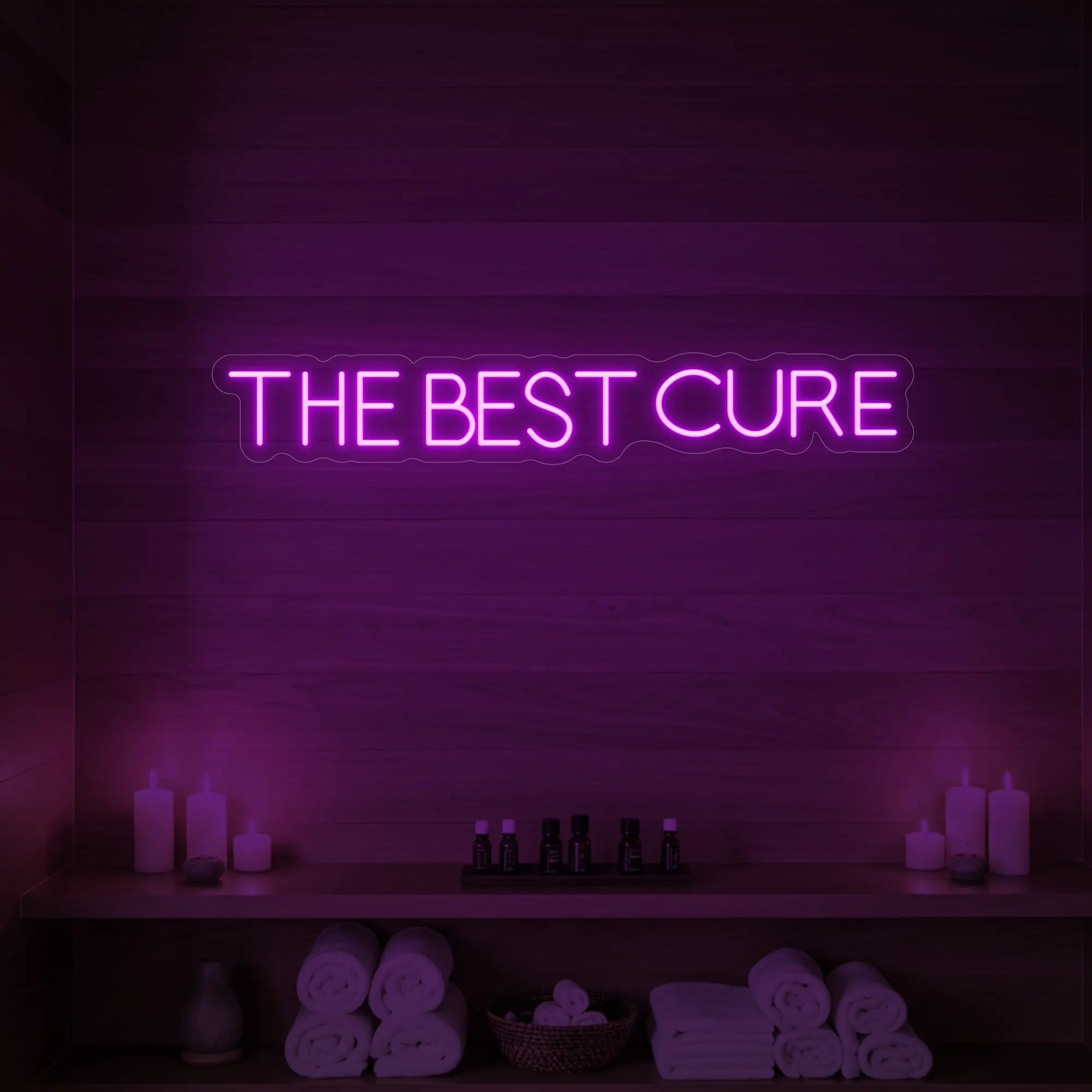 Photo of the 'The Best Cure' neon sign glowing in deep pink against a styled interior wall.