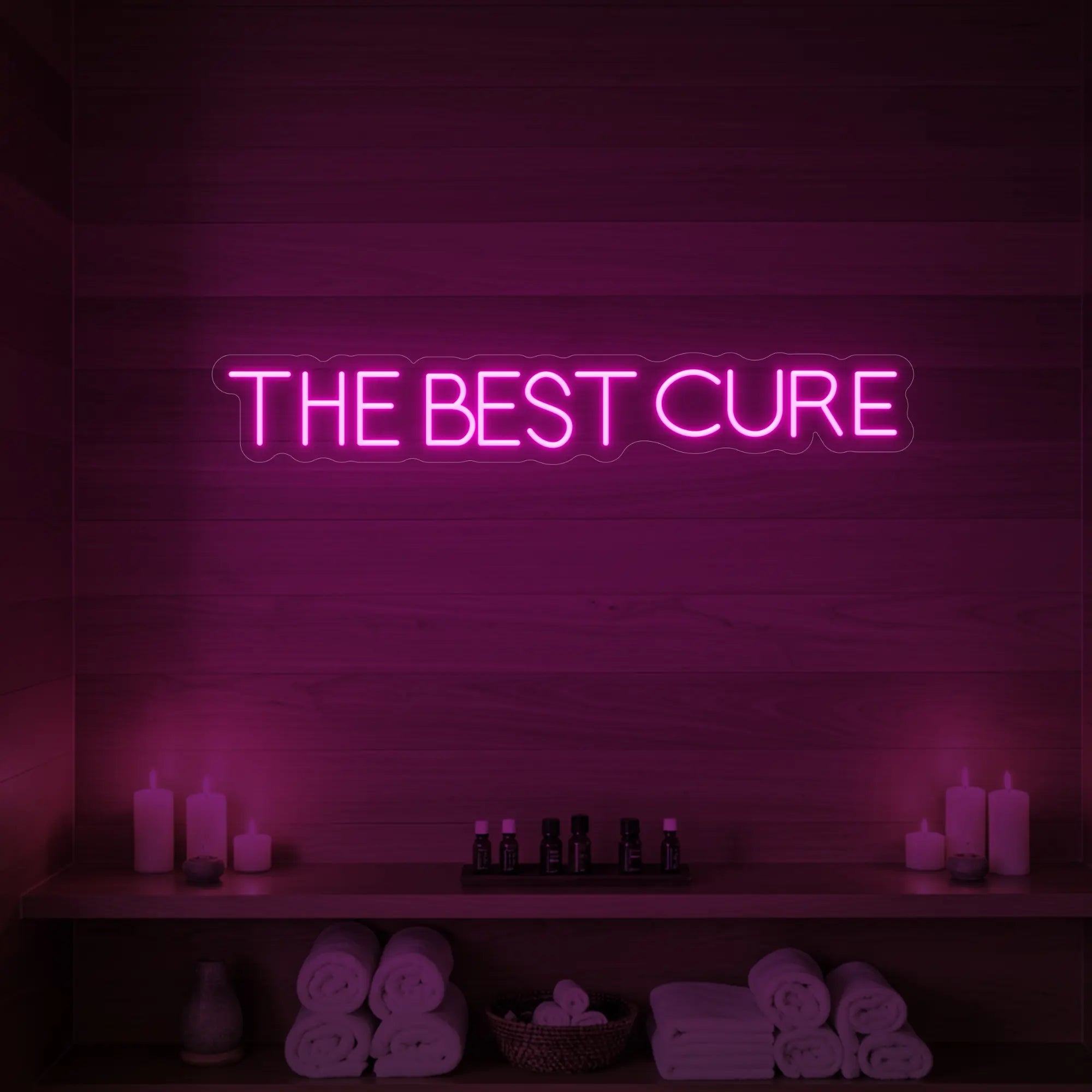 Photo of the 'The Best Cure' neon sign glowing in light pink against a styled interior wall.