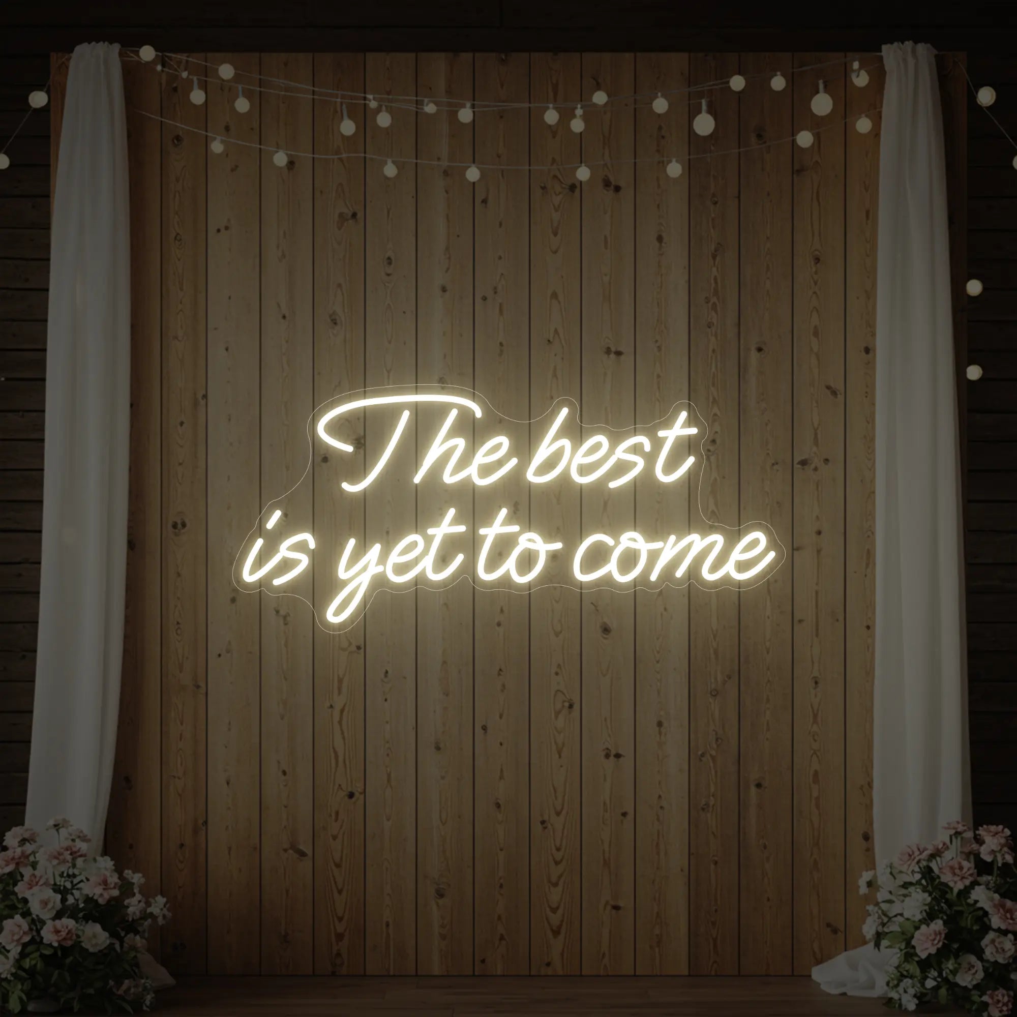 'The Best Is Yet To Come' neon sign glowing in warm white against a styled interior wall.