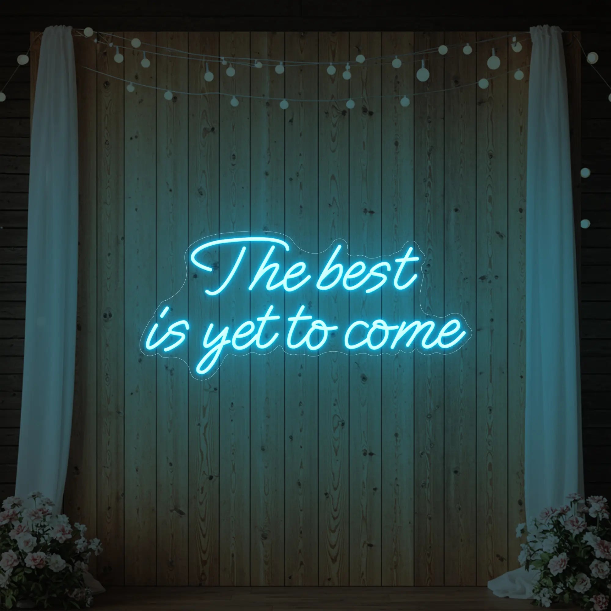 'The Best Is Yet To Come' neon sign glowing in ice blue against a styled interior wall.