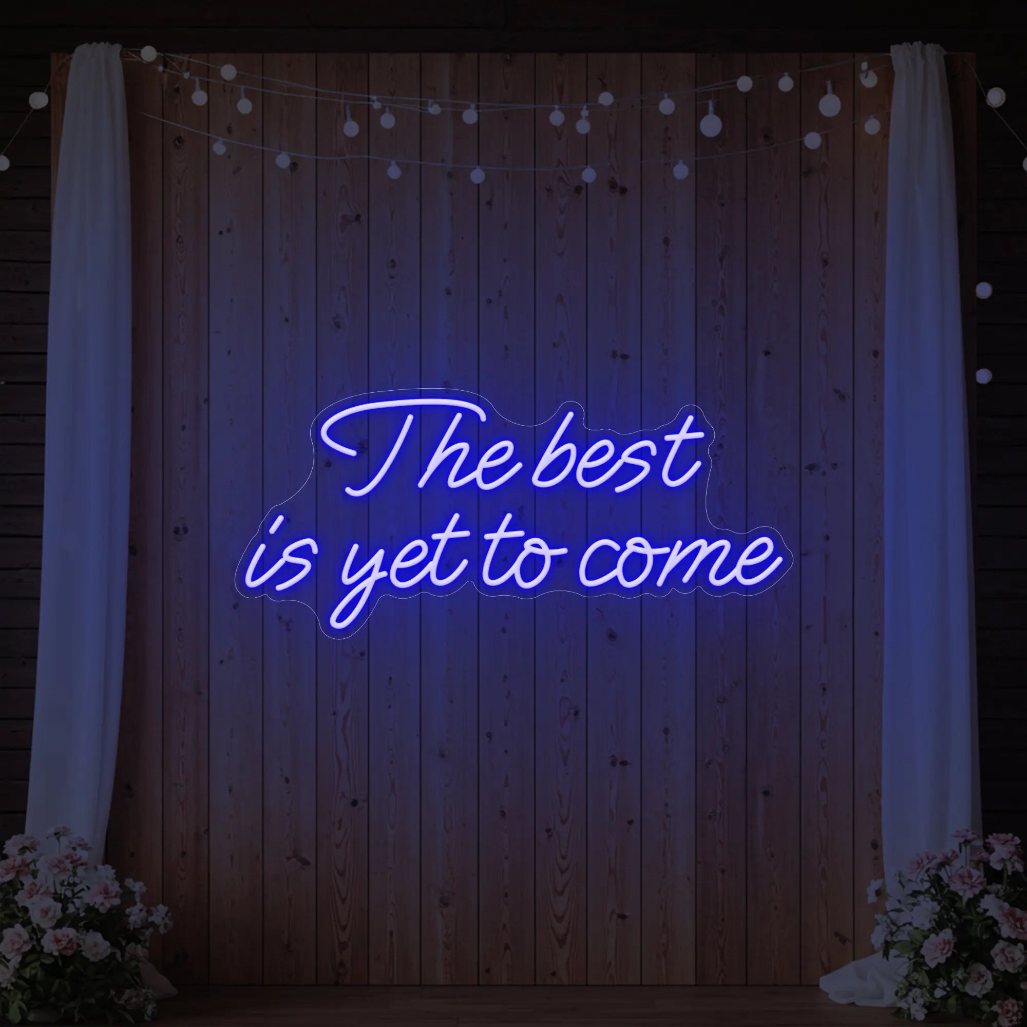 'The Best Is Yet To Come' neon sign glowing in deep blue against a styled interior wall.