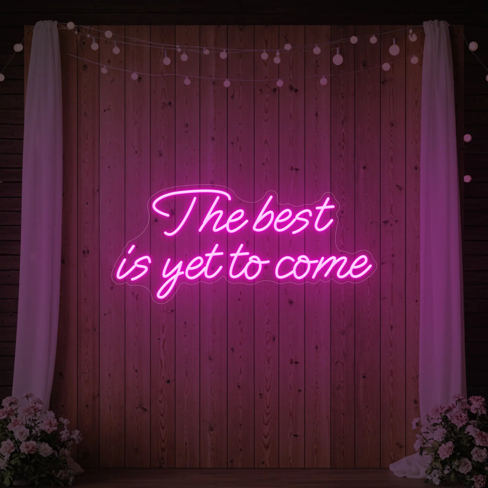 'The Best Is Yet To Come' neon sign glowing in deep pink against a styled interior wall.