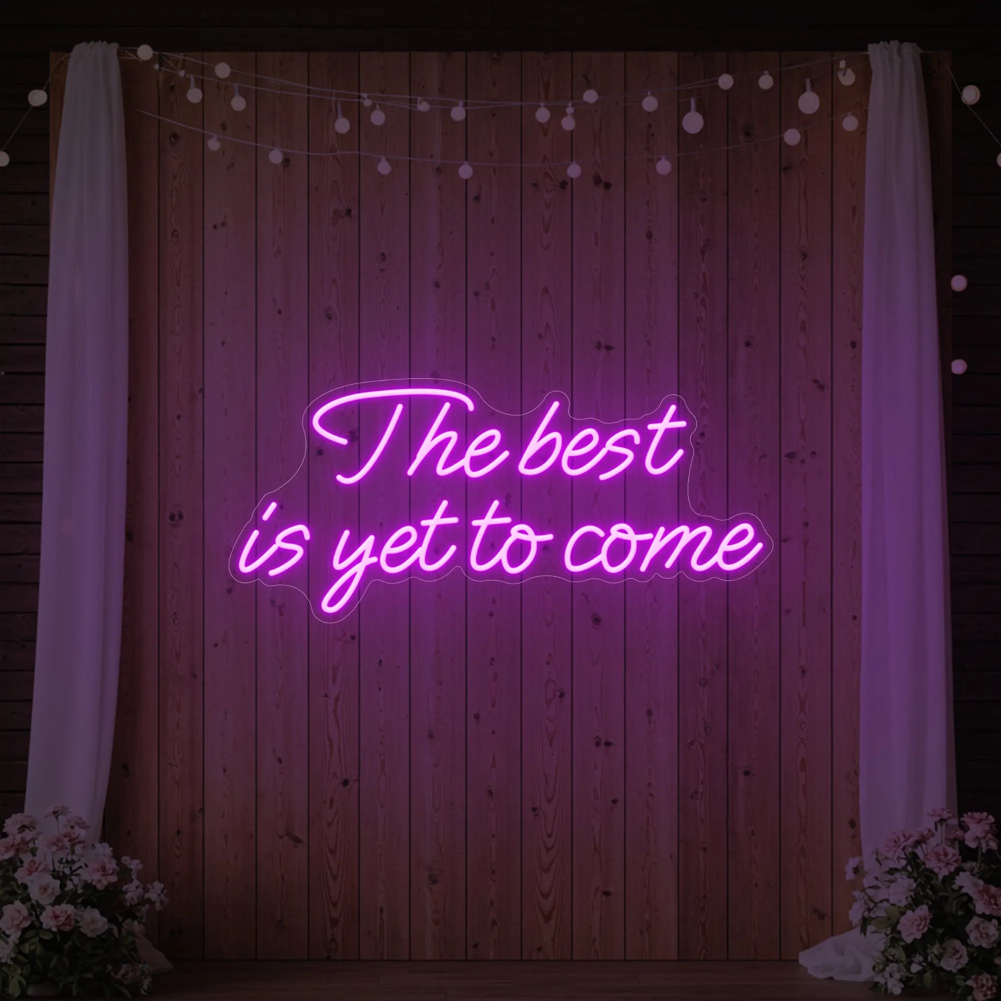 'The Best Is Yet To Come' neon sign glowing in light pink against a styled interior wall.