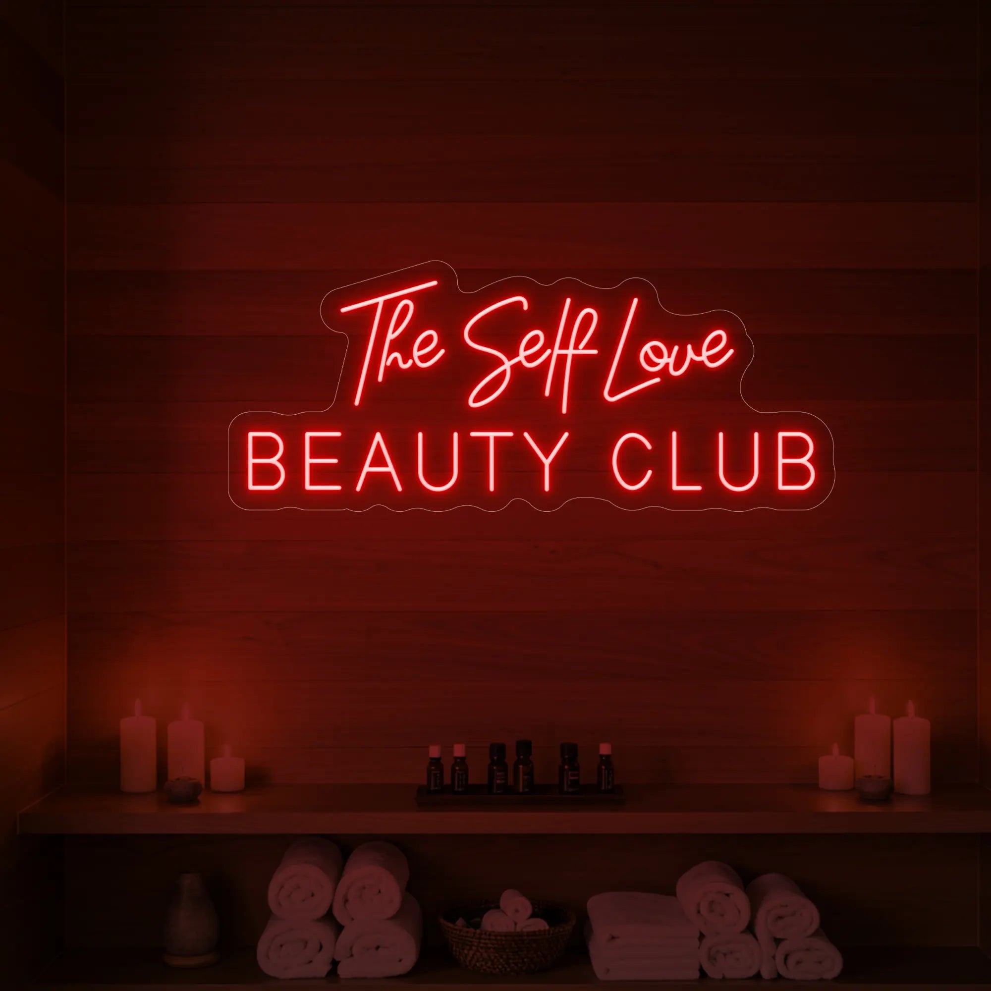 Photo of the 'The Self Love Beauty Club' neon sign glowing in red against a styled interior wall.