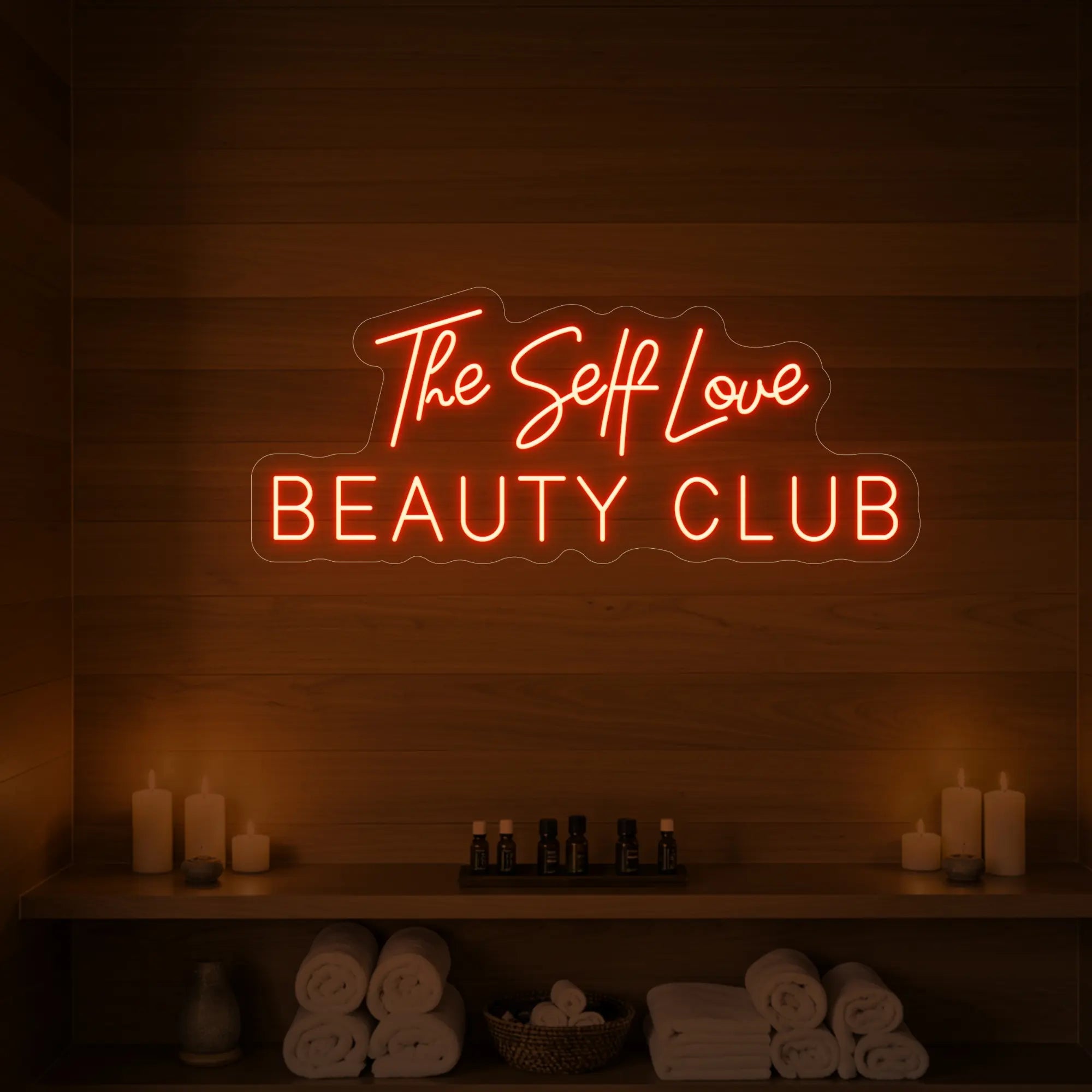 Photo of the 'The Self Love Beauty Club' neon sign glowing in golden yellow against a styled interior wall.