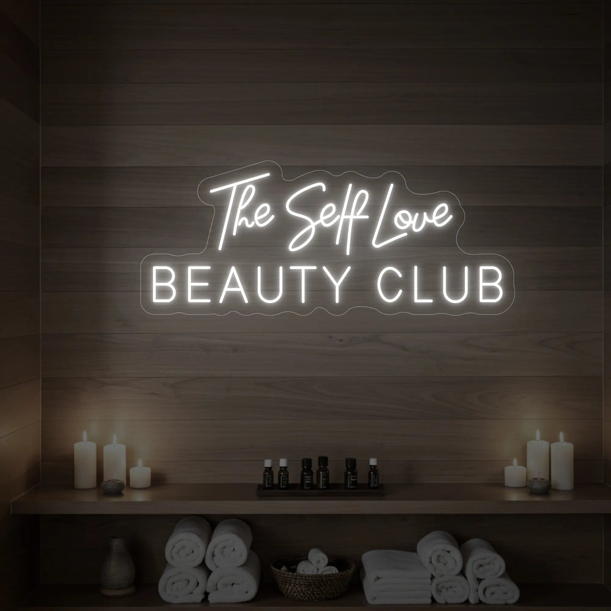 Photo of the 'The Self Love Beauty Club' neon sign glowing in cool white against a styled interior wall.