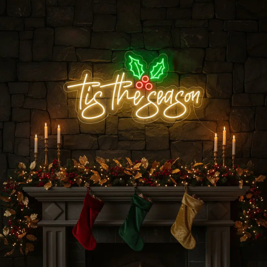 Photo of the 'Tis The Season With Mistletoe' neon sign glowing in multicolor against a styled interior wall.