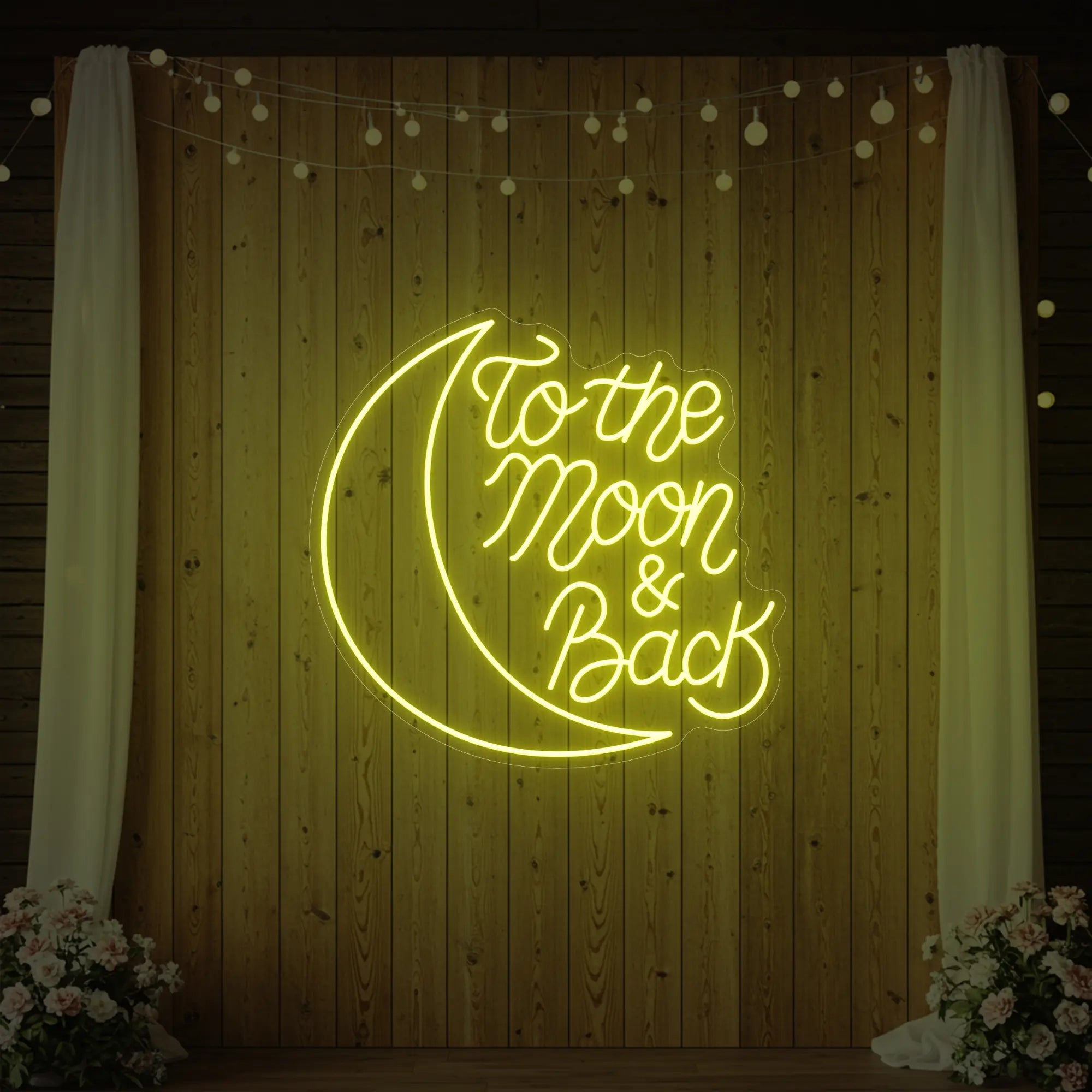 'To The Moon & Back' neon sign glowing in lemon yellow against a styled interior wall.