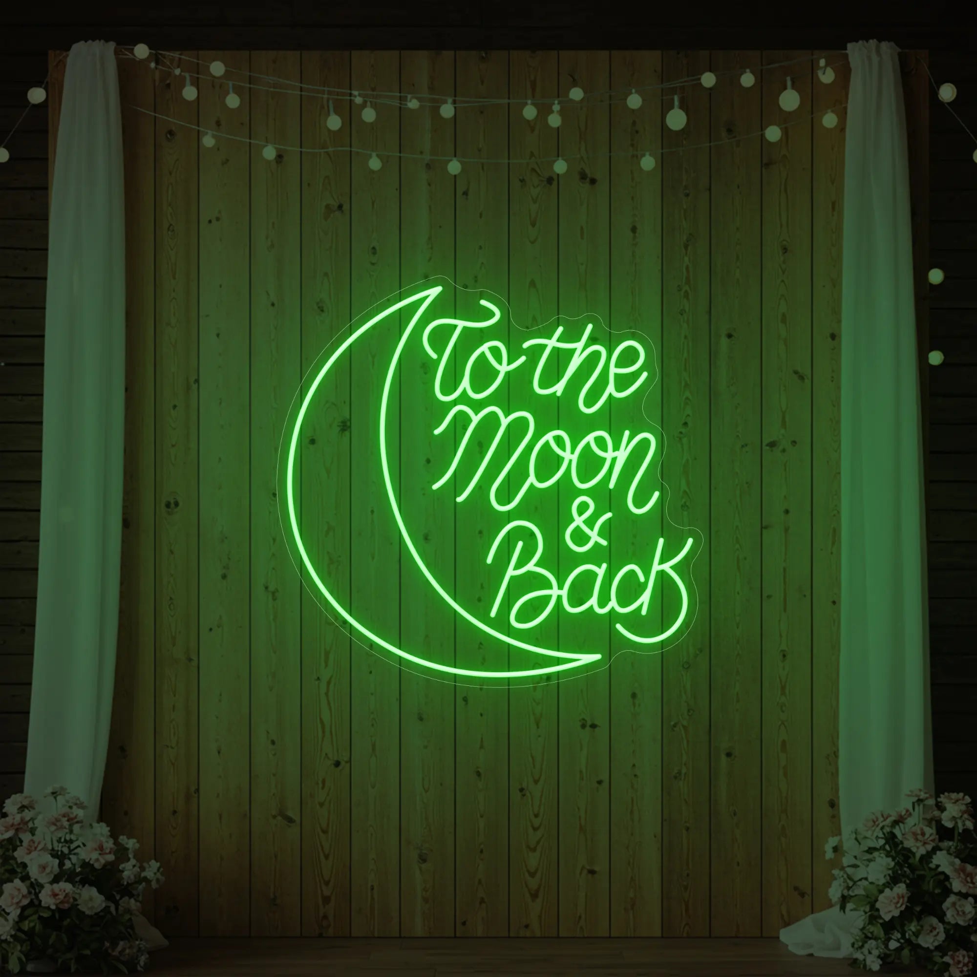 'To The Moon & Back' neon sign glowing in green against a styled interior wall.