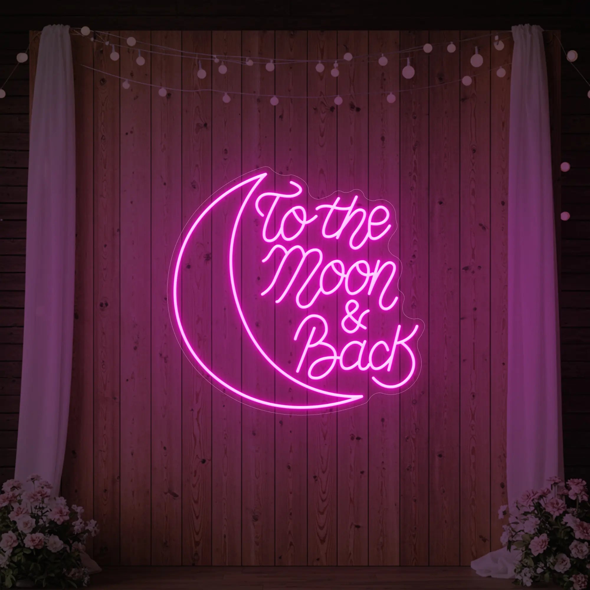 'To The Moon & Back' neon sign glowing in light pink against a styled interior wall.