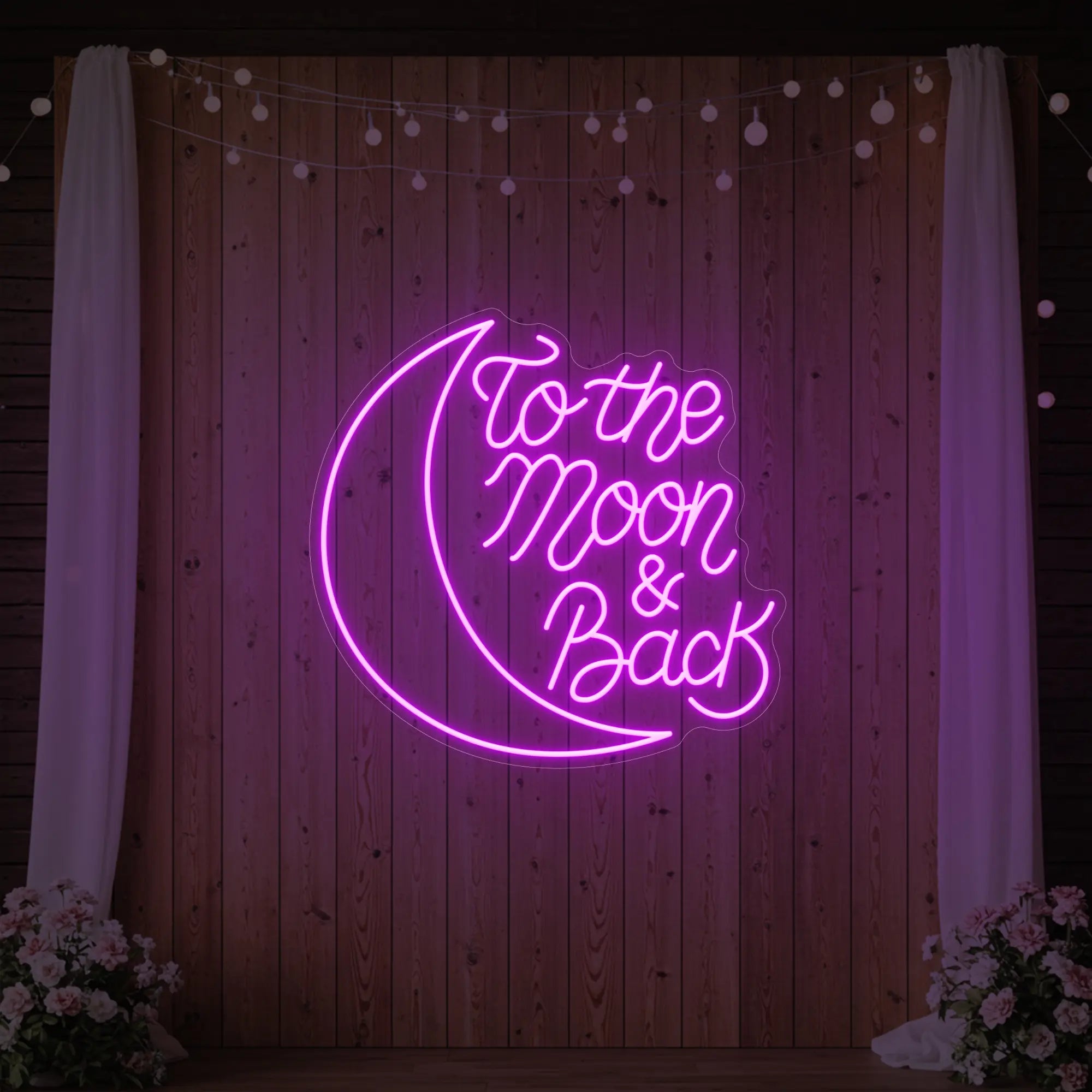 'To The Moon & Back' neon sign glowing in deep pink against a styled interior wall.