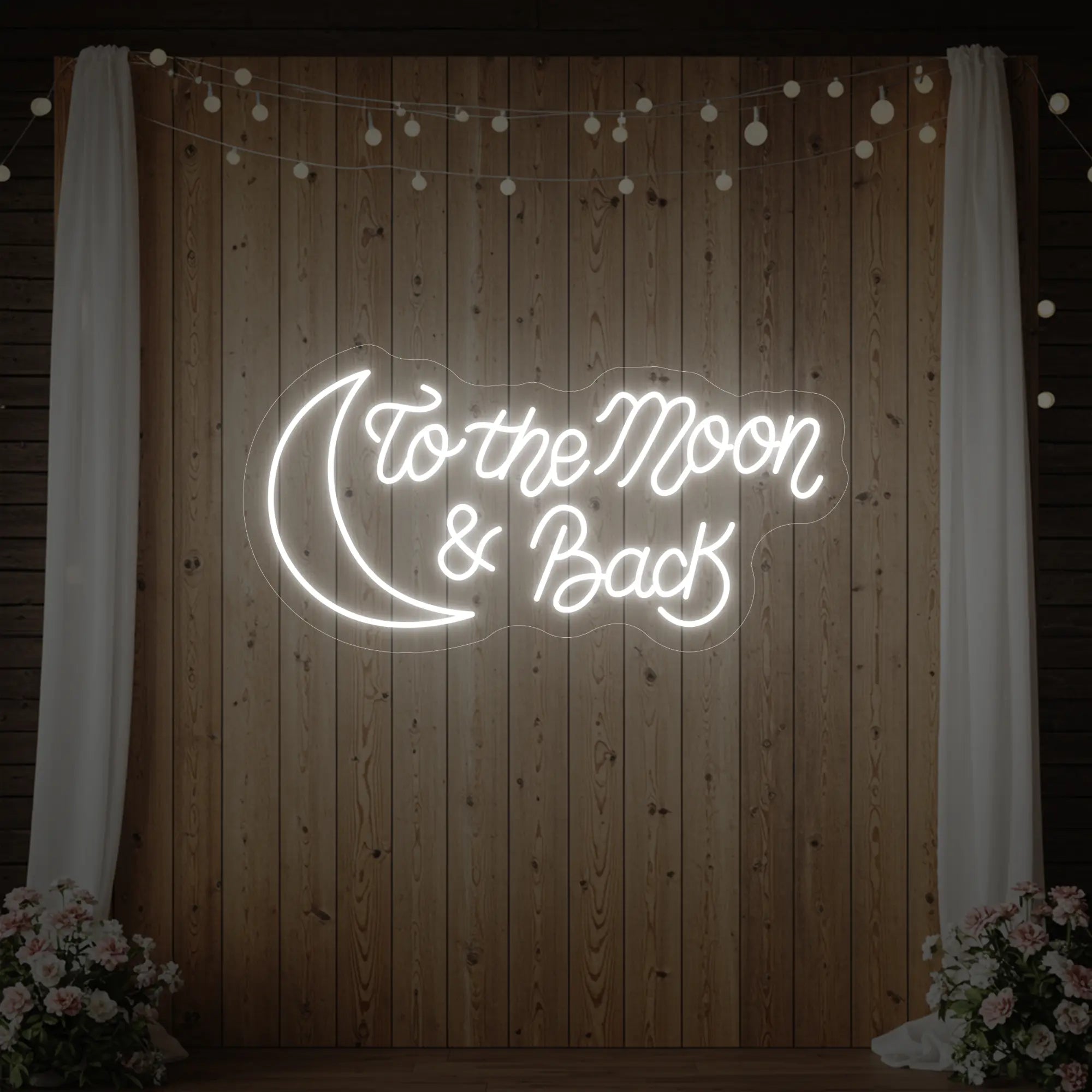 'To The Moon And Back' neon sign glowing in cool white against a styled interior wall.