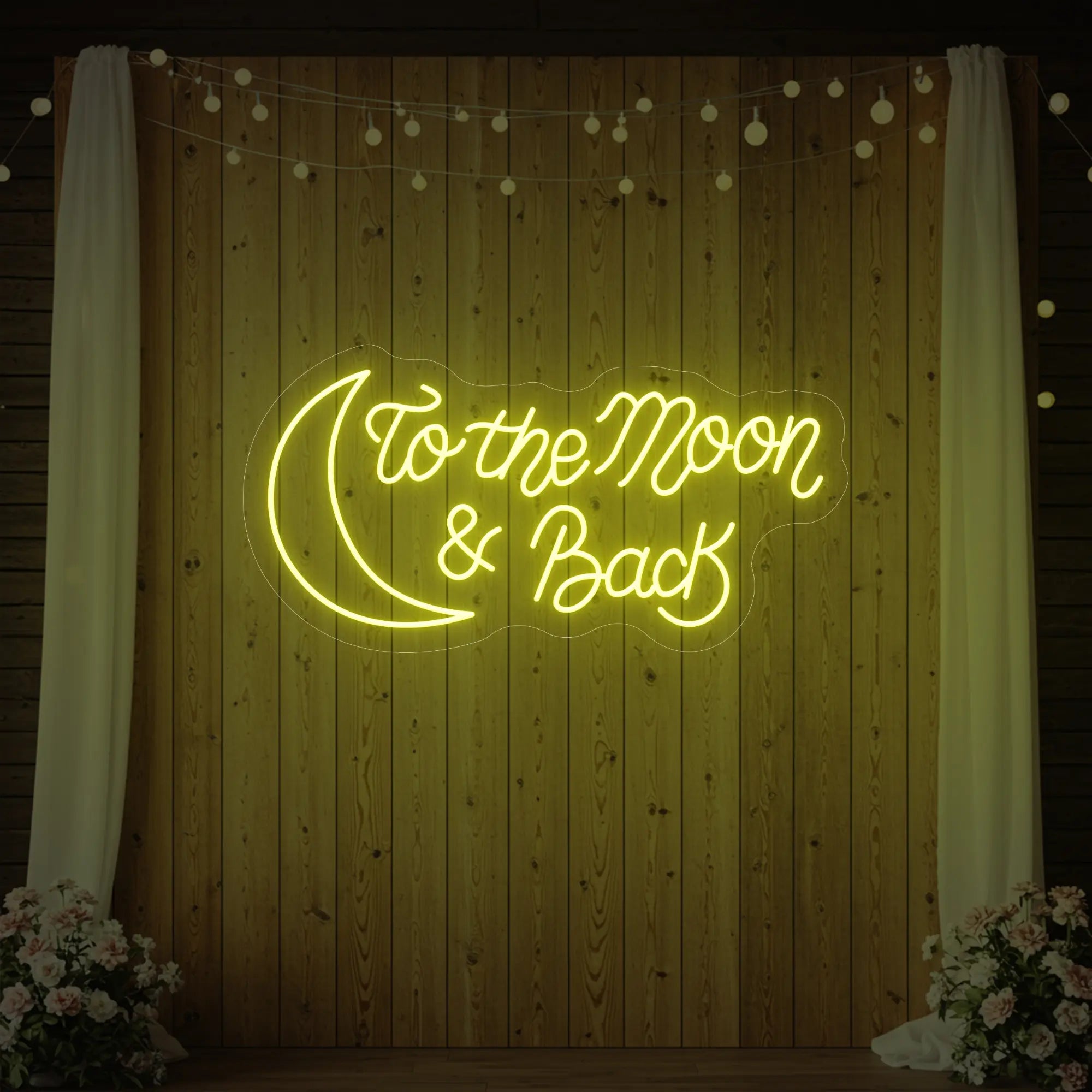 'To The Moon And Back' neon sign glowing in lemon yellow against a styled interior wall.