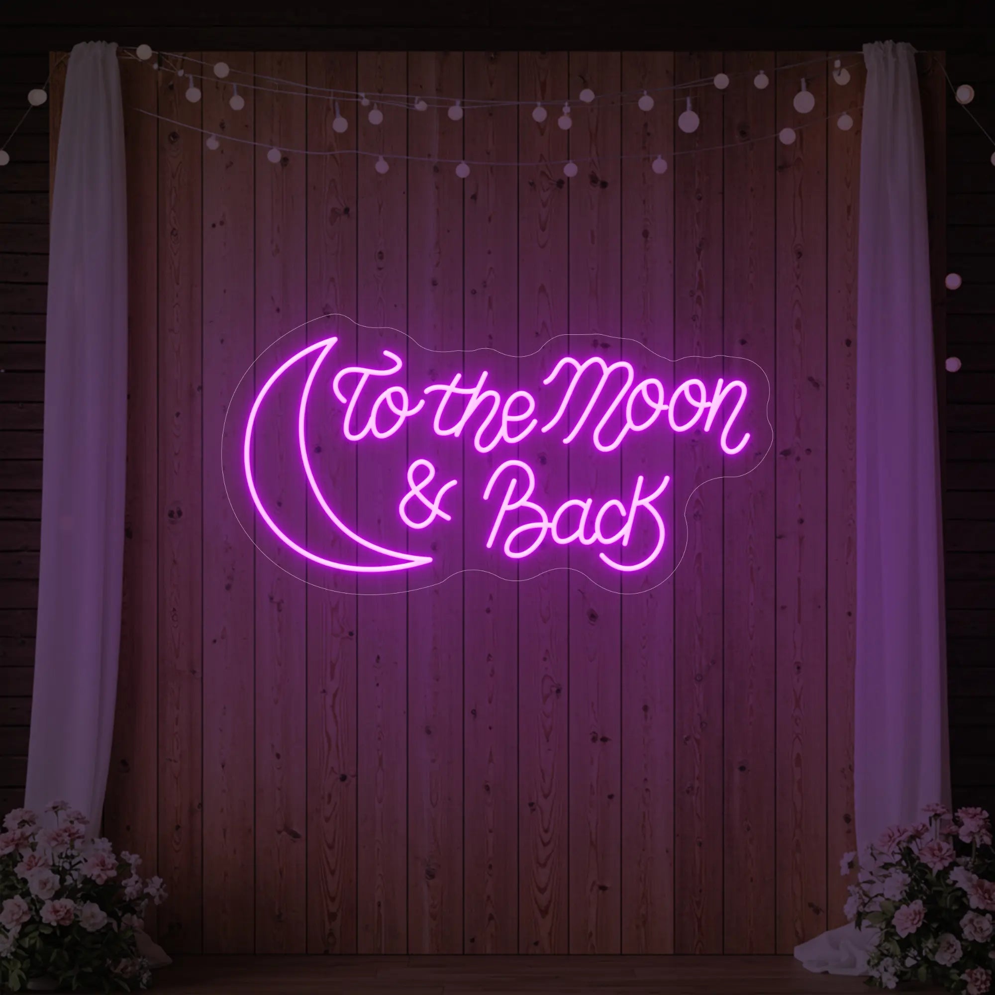 'To The Moon And Back' neon sign glowing in deep pink against a styled interior wall.
