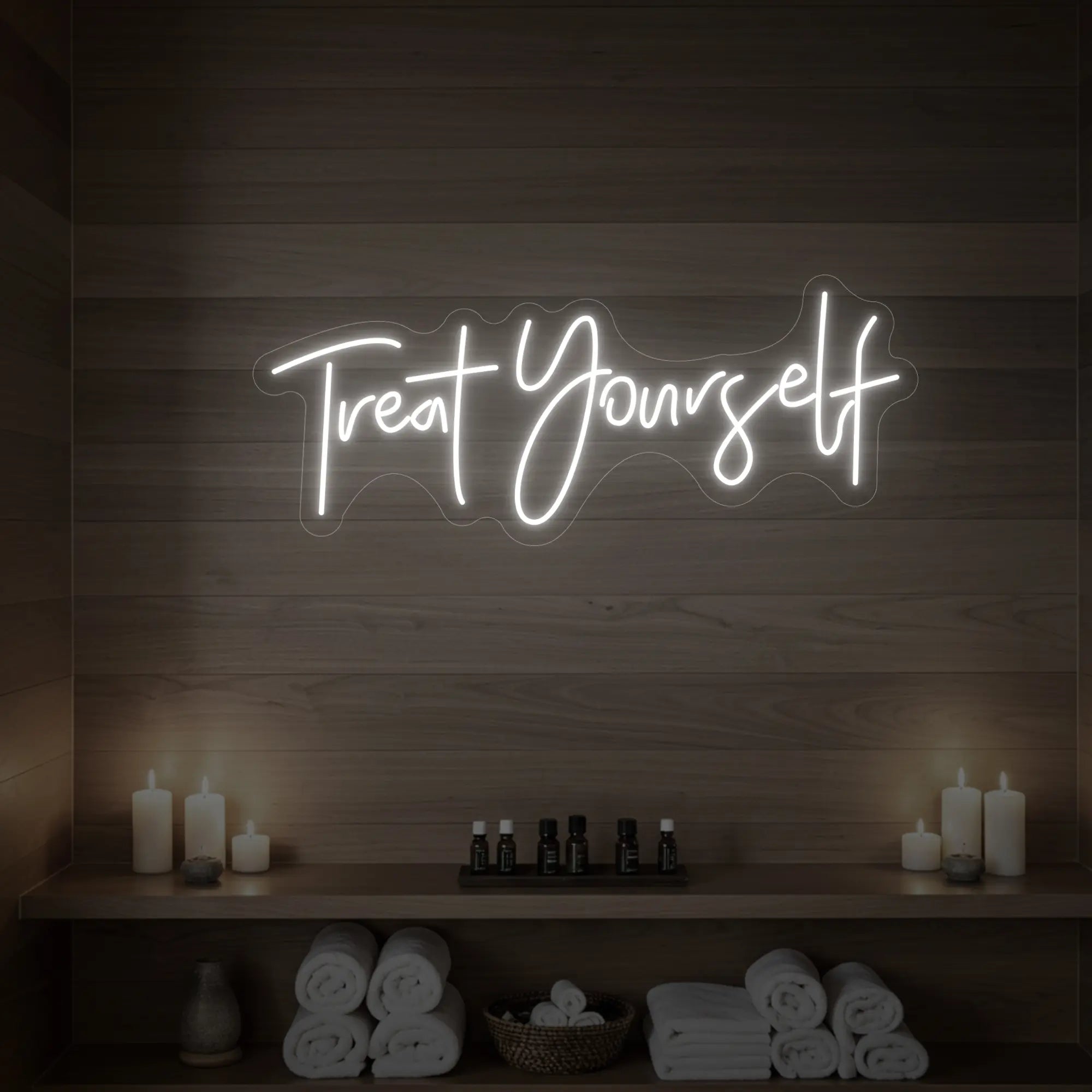 Photo of the 'Treat Yourself' neon sign glowing in cool white against a styled interior wall.