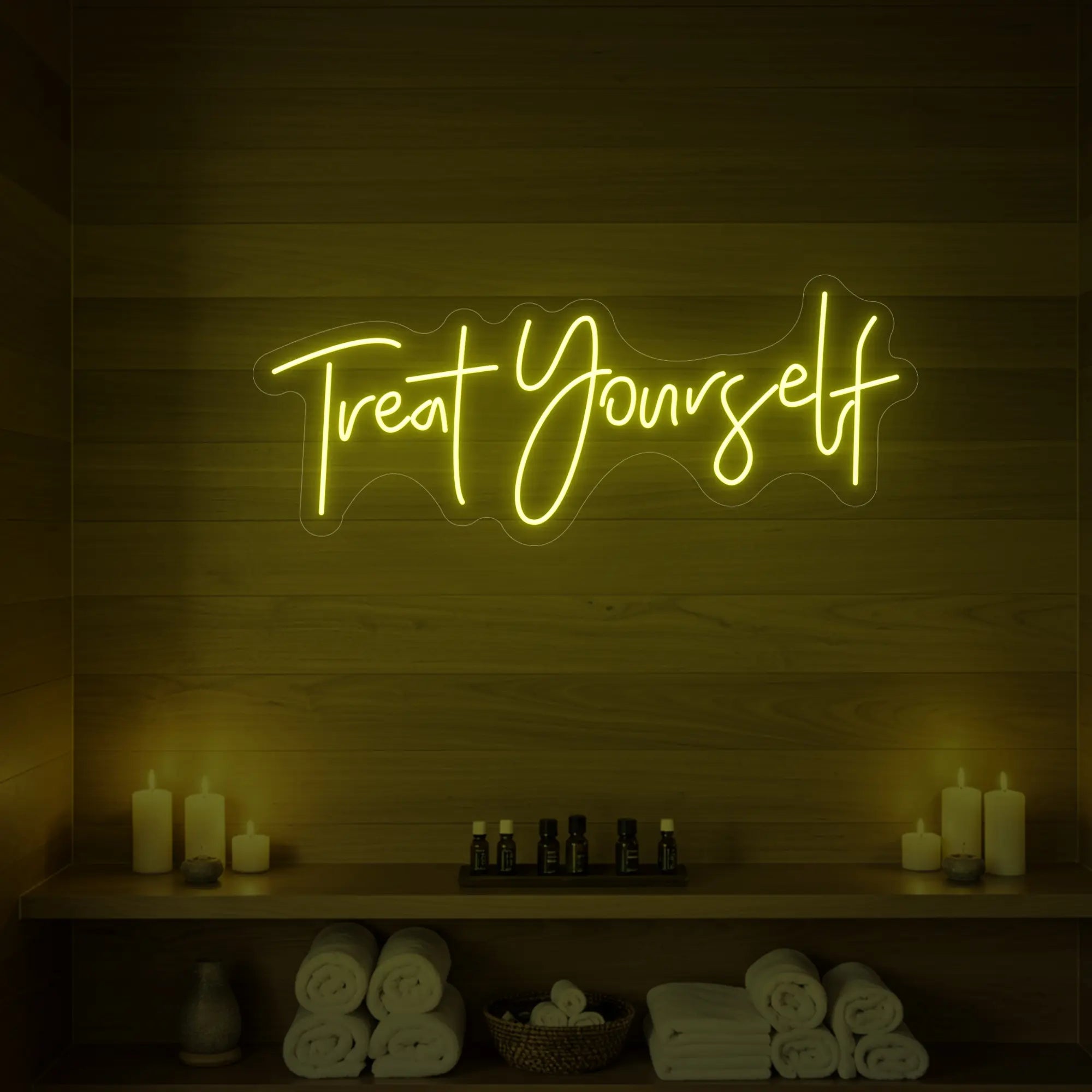 Photo of the 'Treat Yourself' neon sign glowing in lemon yellow against a styled interior wall.
