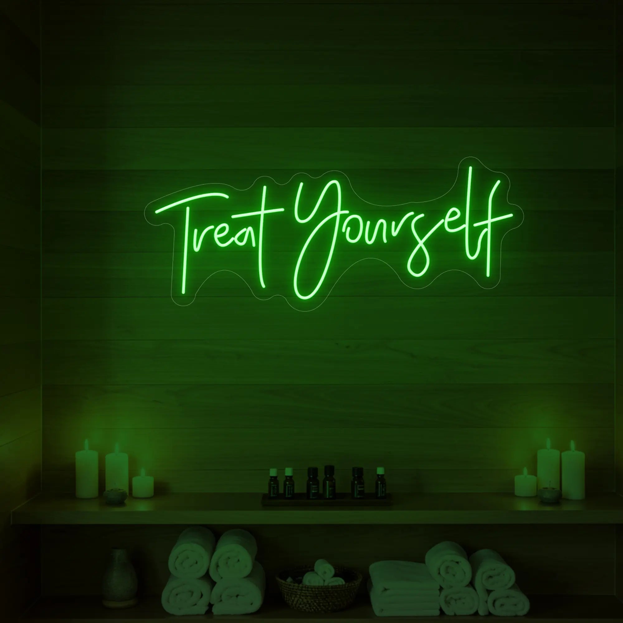 Photo of the 'Treat Yourself' neon sign glowing in green against a styled interior wall.