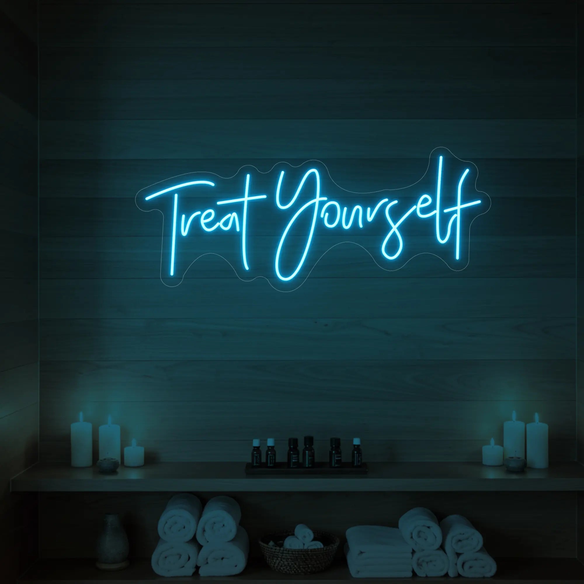 Photo of the 'Treat Yourself' neon sign glowing in ice blue against a styled interior wall.
