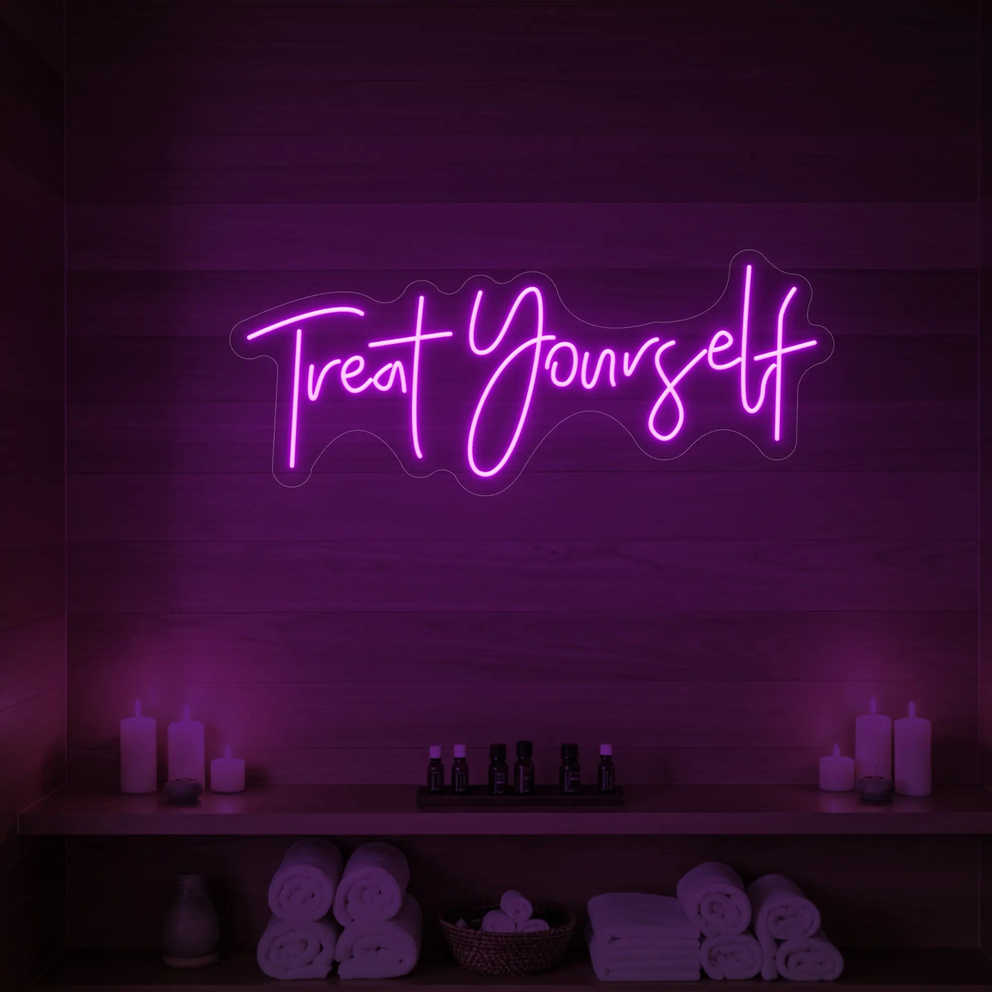 Photo of the 'Treat Yourself' neon sign glowing in deep pink against a styled interior wall.
