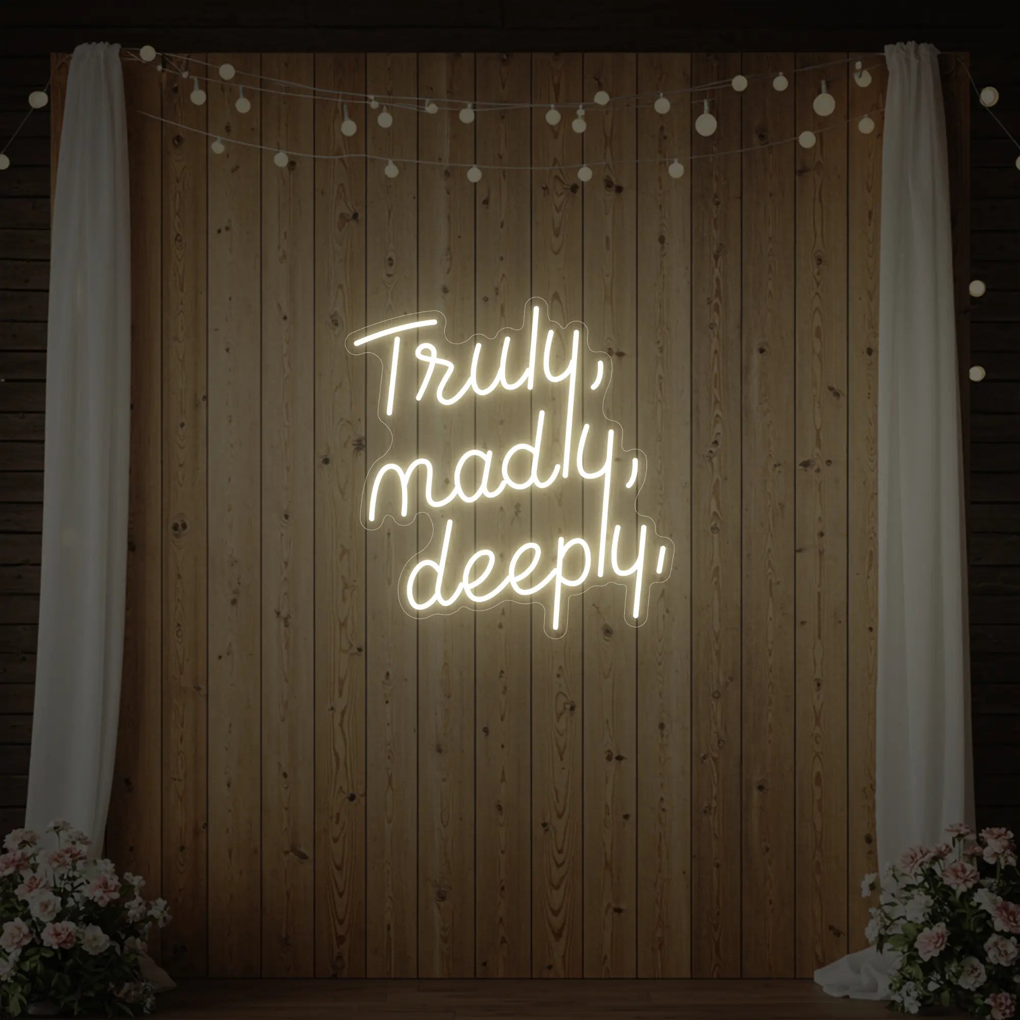 'Truly, Madly, Deeply' neon sign glowing in warm white against a styled interior wall.