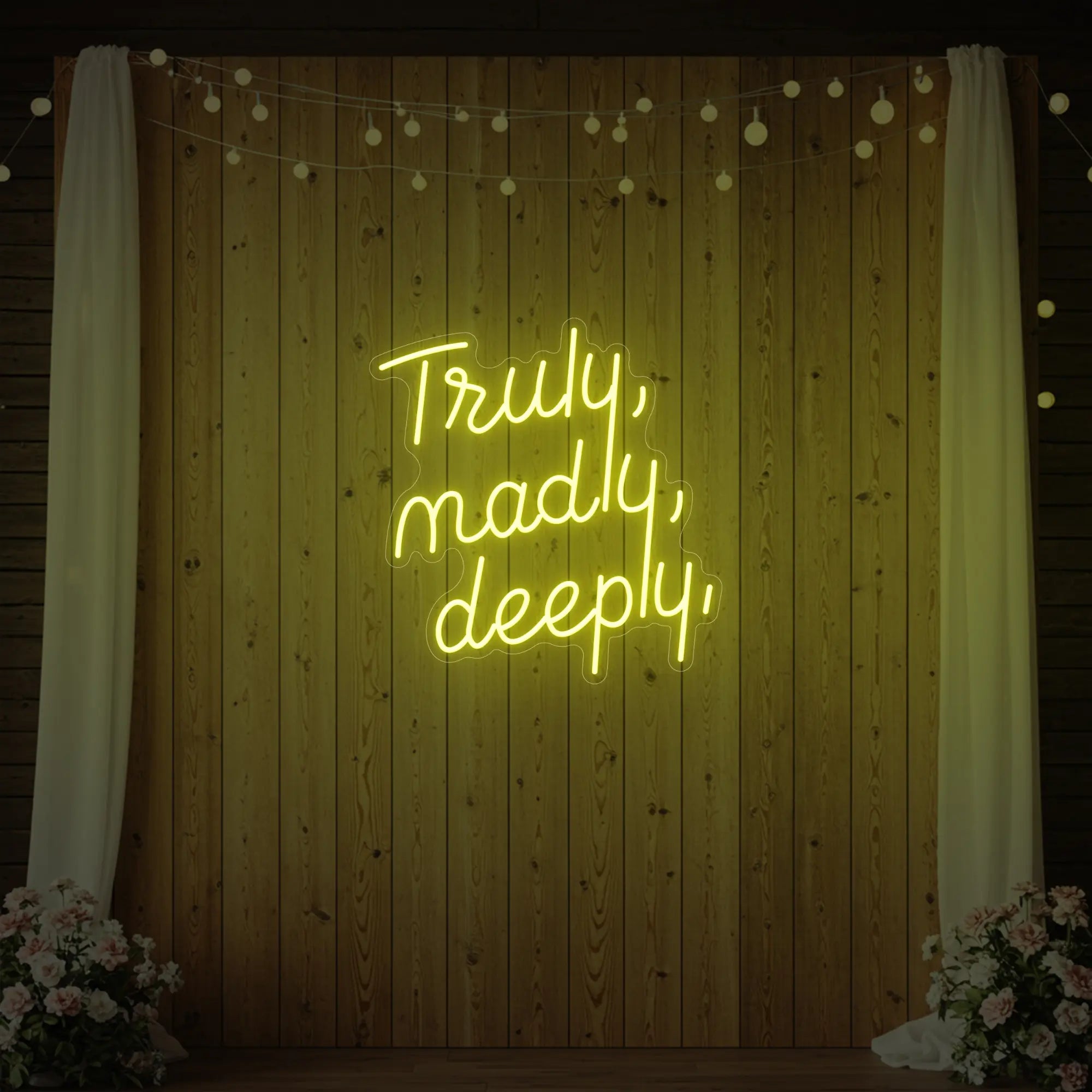 'Truly, Madly, Deeply' neon sign glowing in lemon yellow against a styled interior wall.