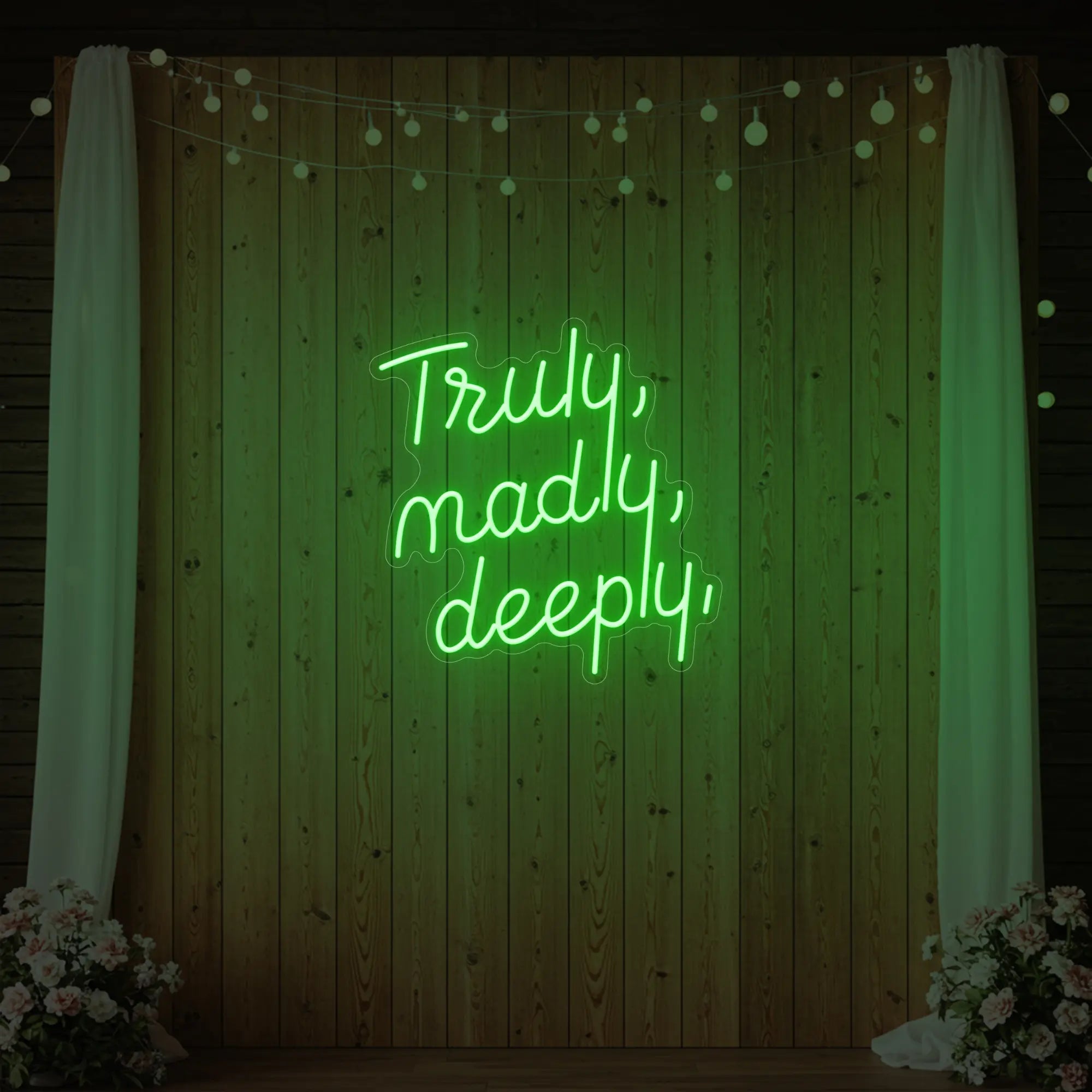 'Truly, Madly, Deeply' neon sign glowing in green against a styled interior wall.