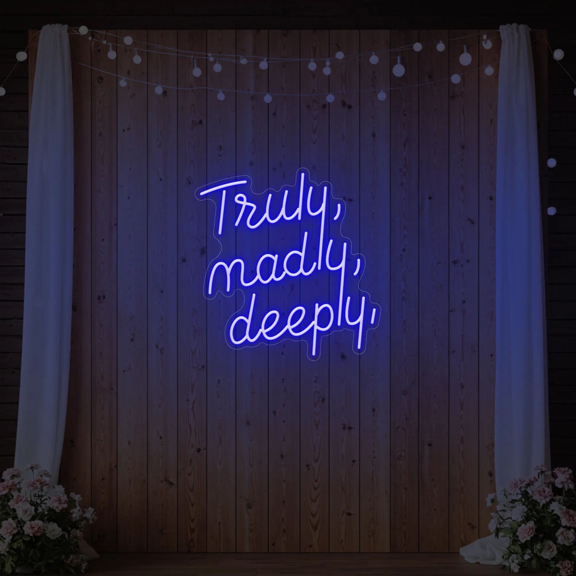 'Truly, Madly, Deeply' neon sign glowing in deep blue against a styled interior wall.