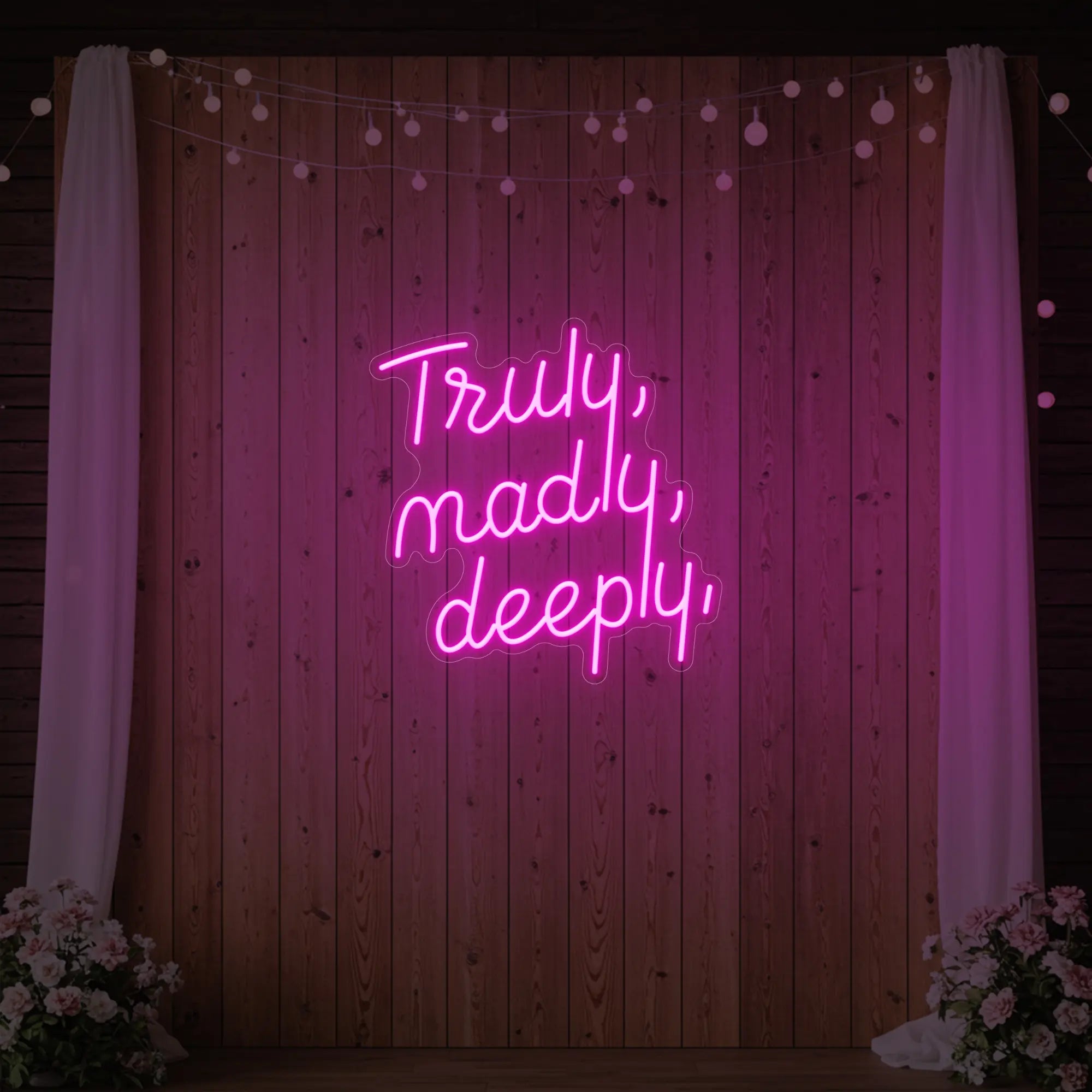 'Truly, Madly, Deeply' neon sign glowing in light pink against a styled interior wall.
