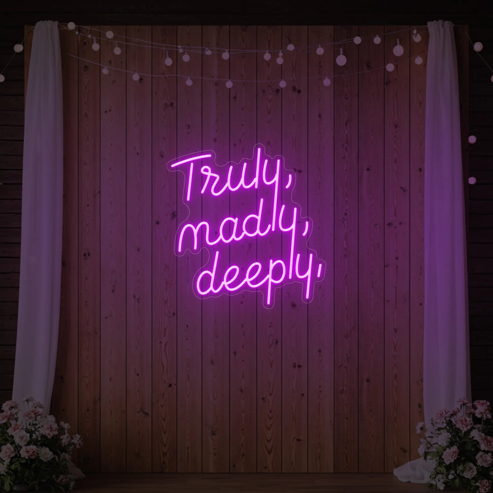 'Truly, Madly, Deeply' neon sign glowing in deep pink against a styled interior wall.