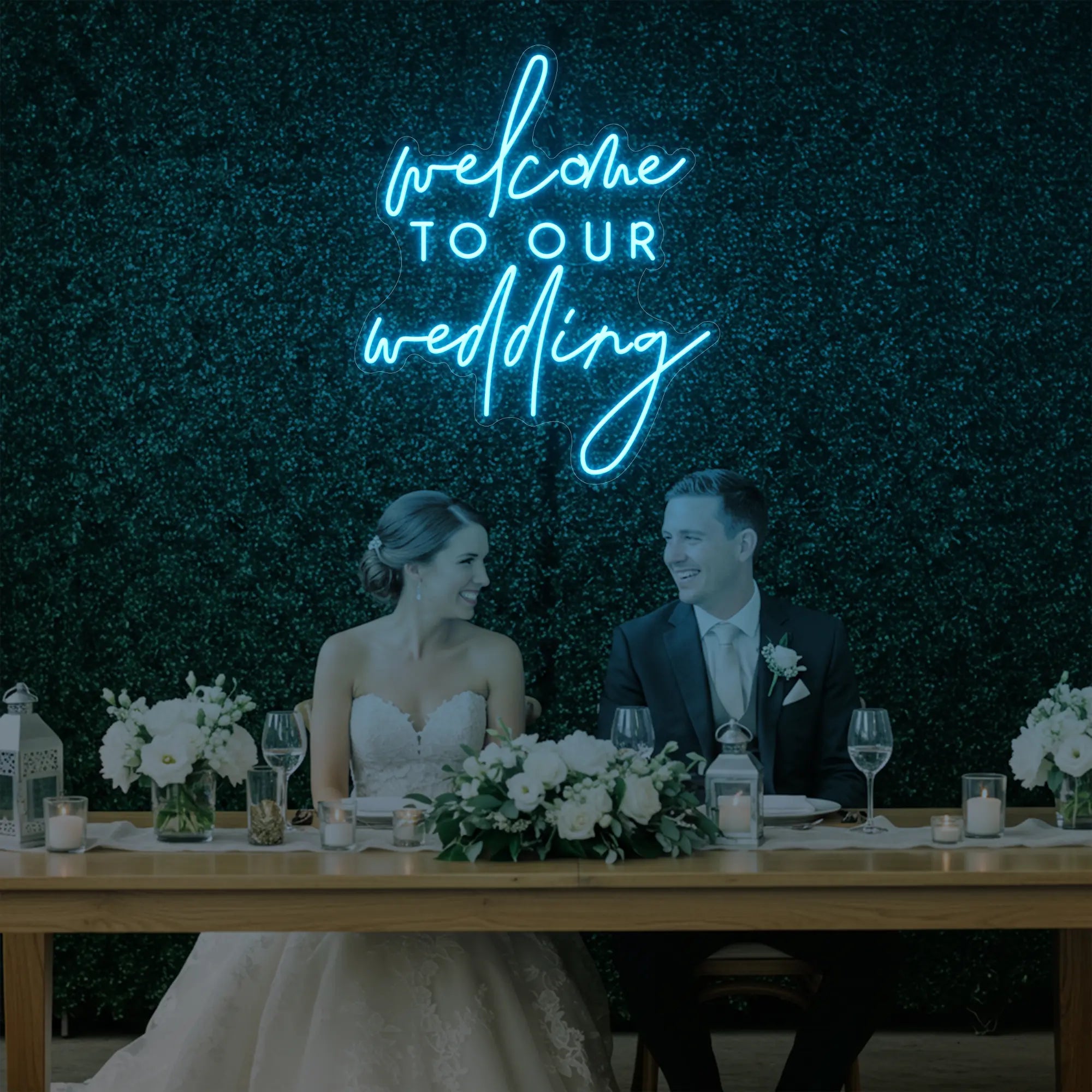 'Welcome To Our Wedding' neon sign glowing in ice blue against a styled interior wall.