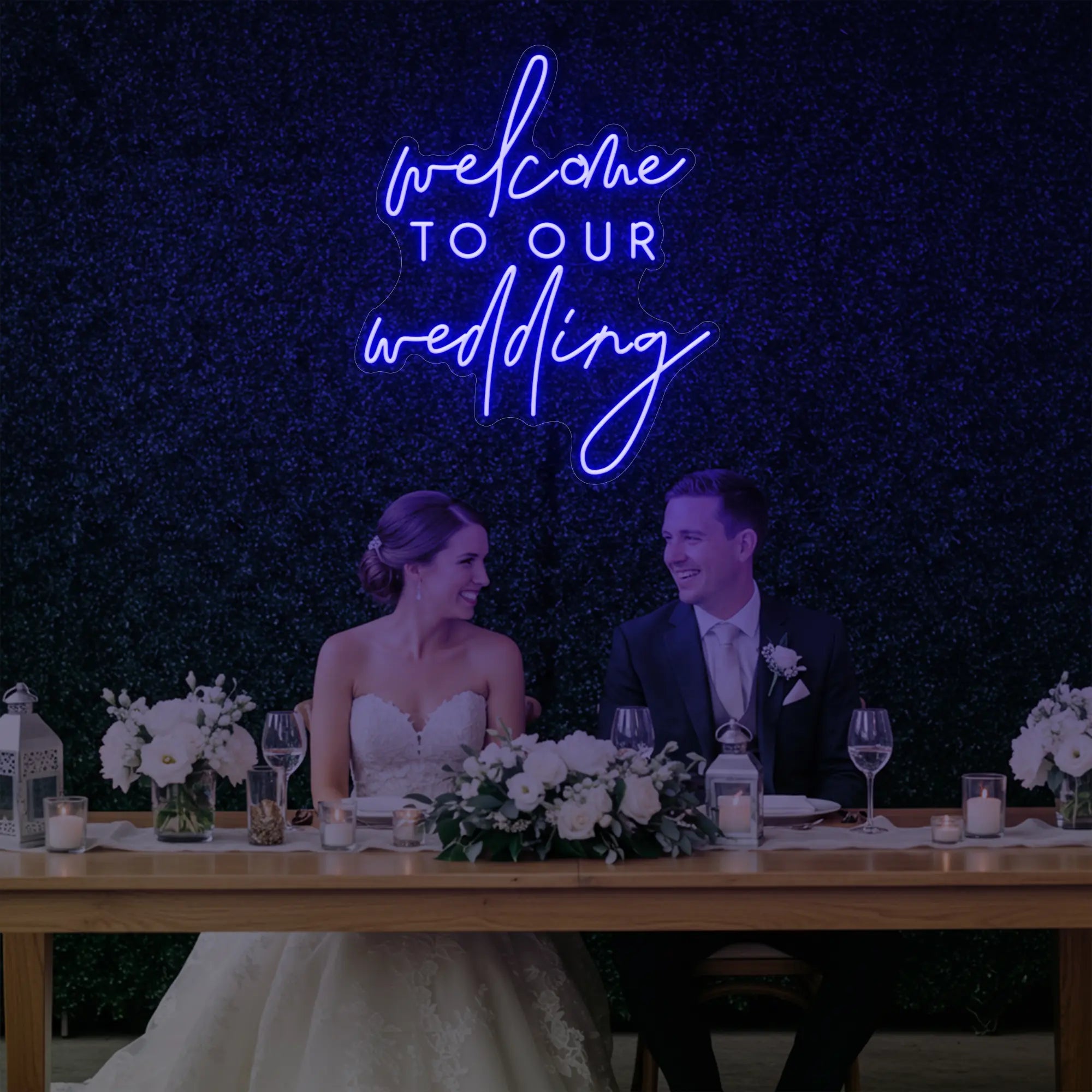 'Welcome To Our Wedding' neon sign glowing in deep blue against a styled interior wall.