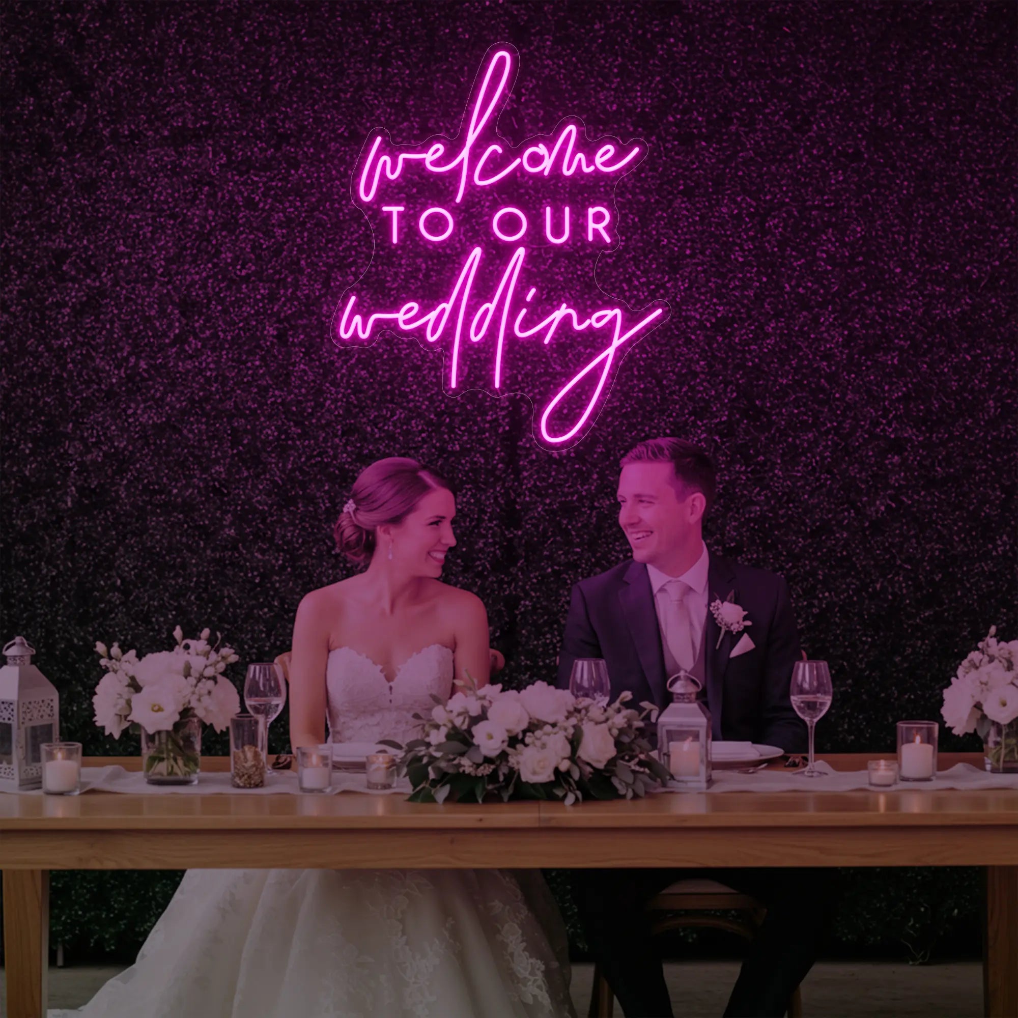 'Welcome To Our Wedding' neon sign glowing in light pink against a styled interior wall.