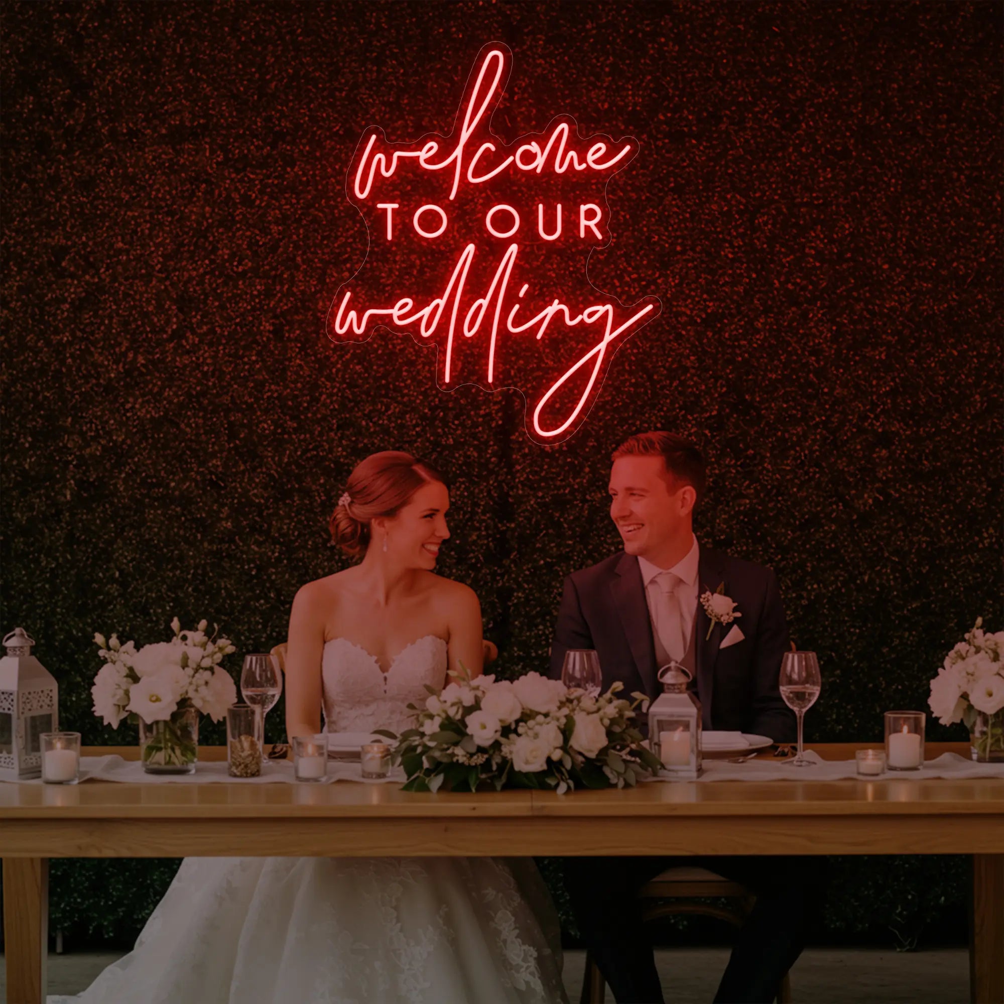 'Welcome To Our Wedding' neon sign glowing in red against a styled interior wall.
