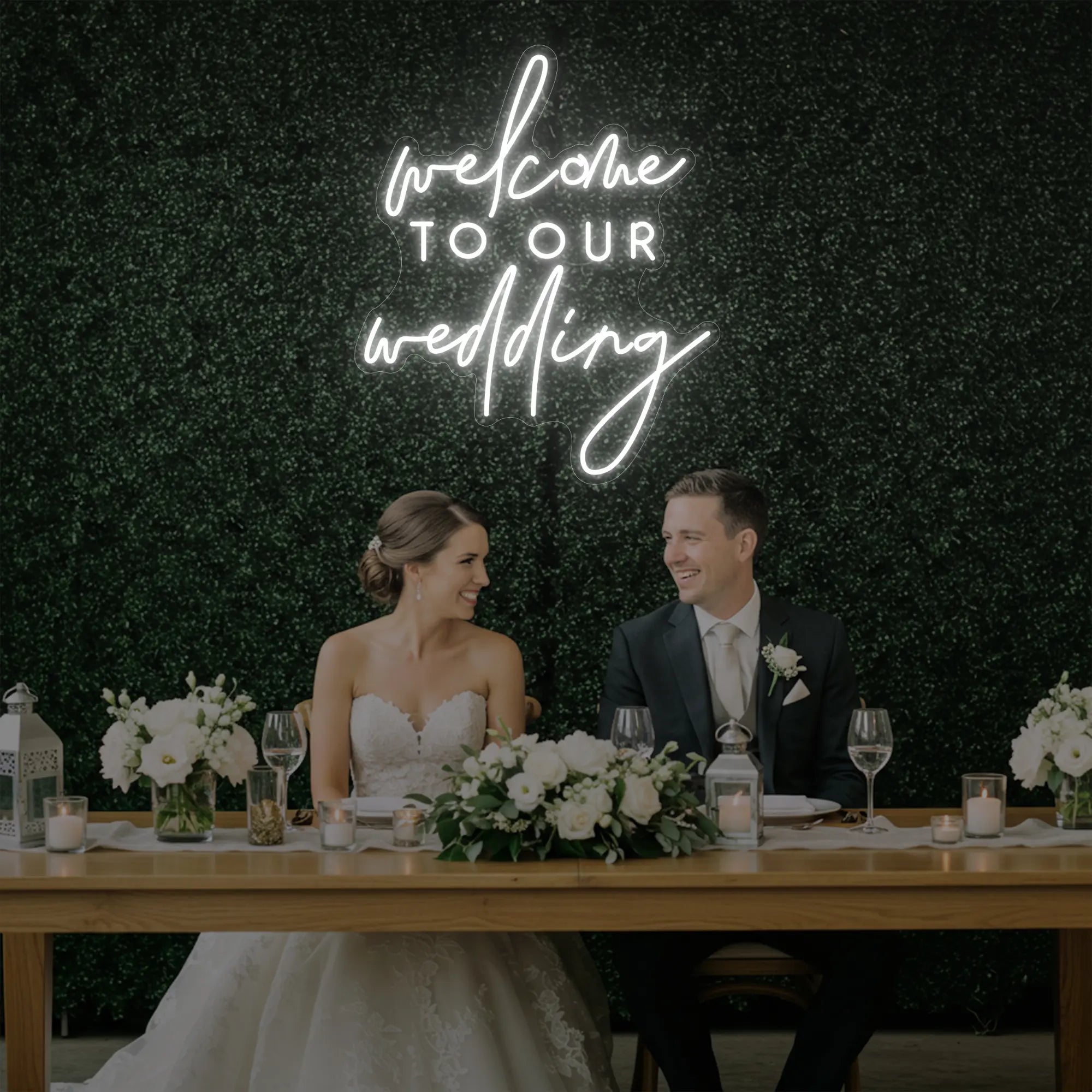 'Welcome To Our Wedding' neon sign glowing in cool white against a styled interior wall.