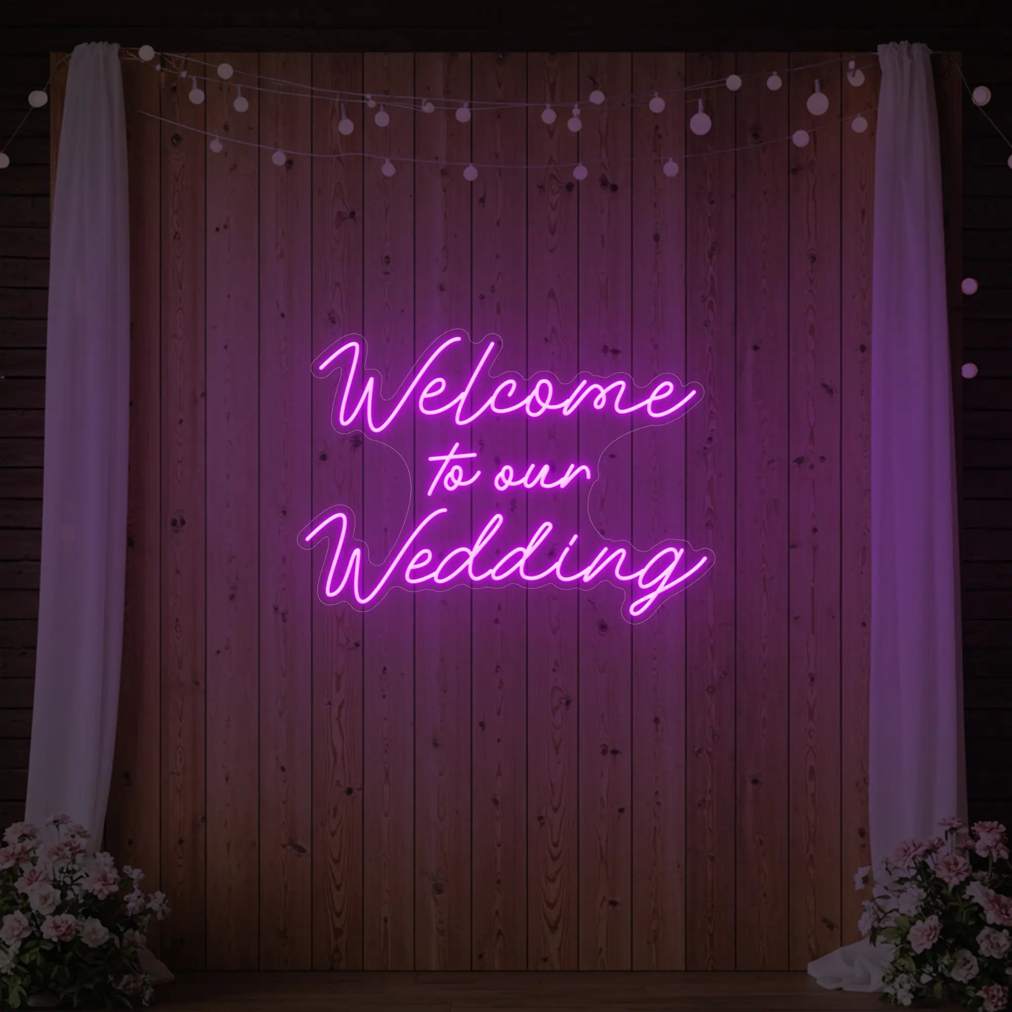 'Welcome To Our Wedding' neon sign glowing in deep pink against a styled interior wall.