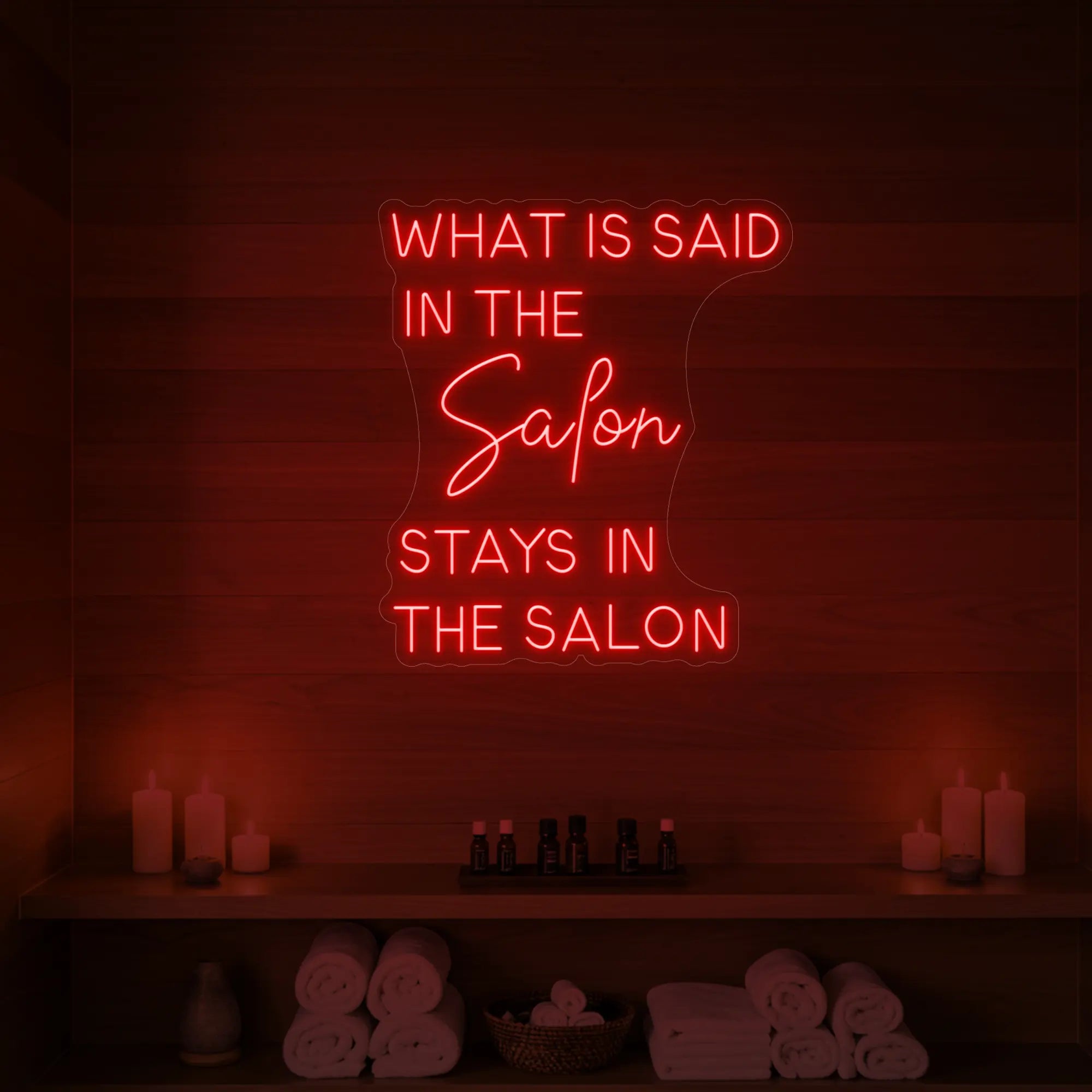 Photo of the 'What is Said in the Salon Stays in the Salon' neon sign glowing in red against a styled interior wall.