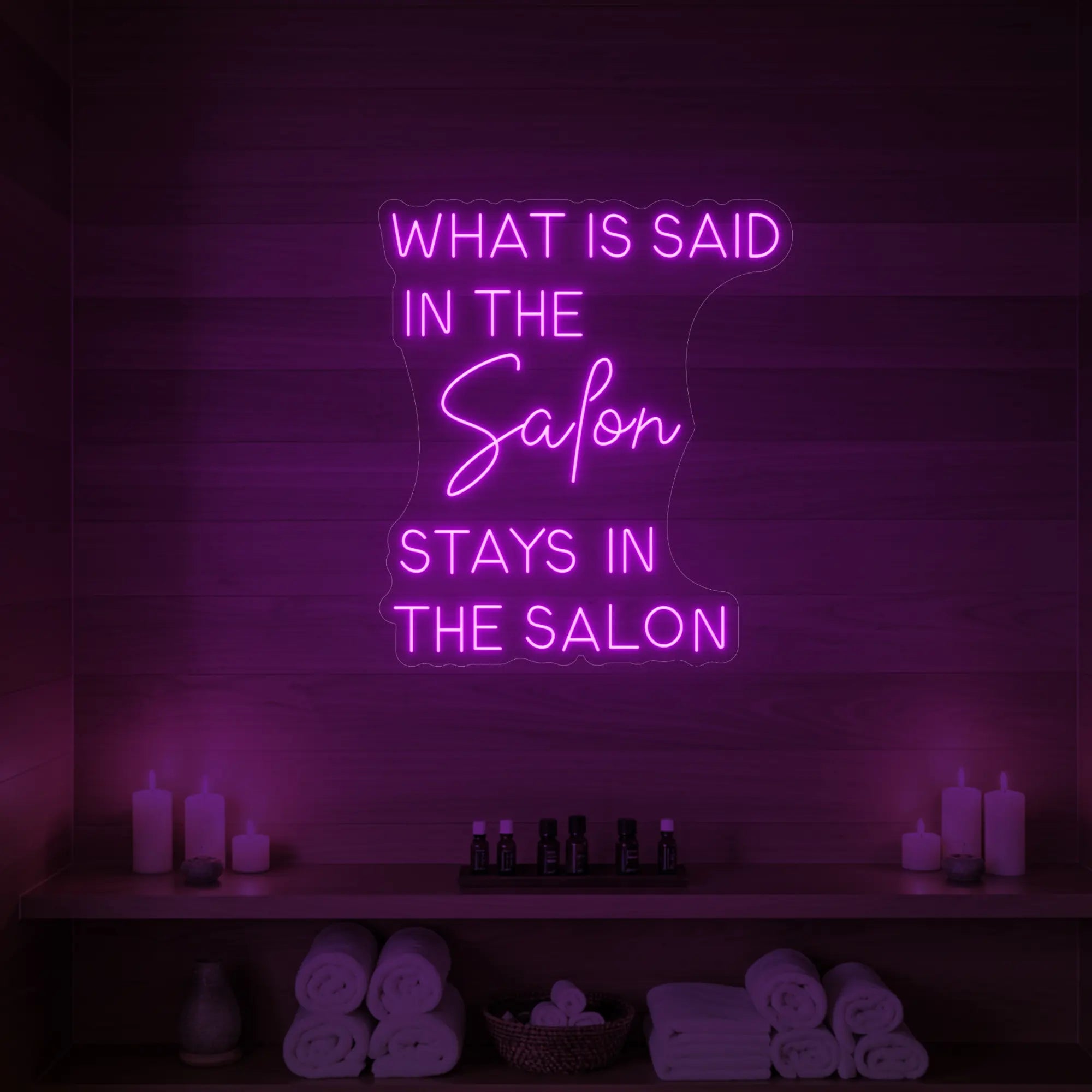Photo of the 'What is Said in the Salon Stays in the Salon' neon sign glowing in deep blue against a styled interior wall.